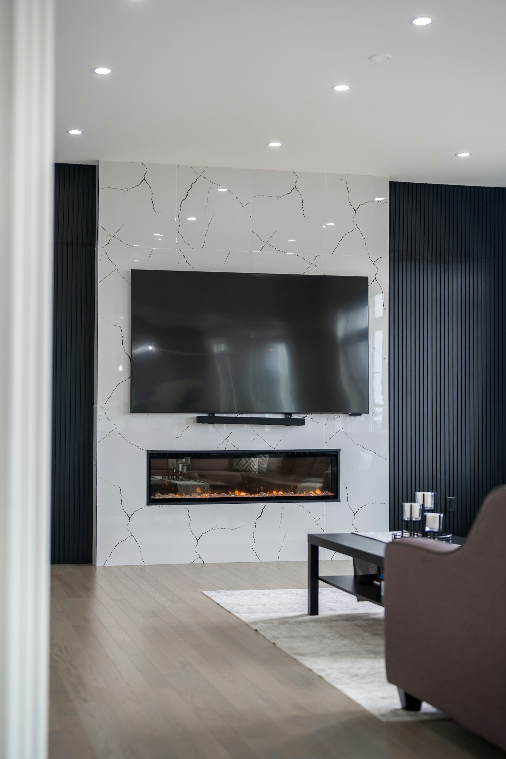 Renovated living room with a modern fireplace, marble look feature wall, and built in television by Michael Moser Contracting in Victoria, BC.