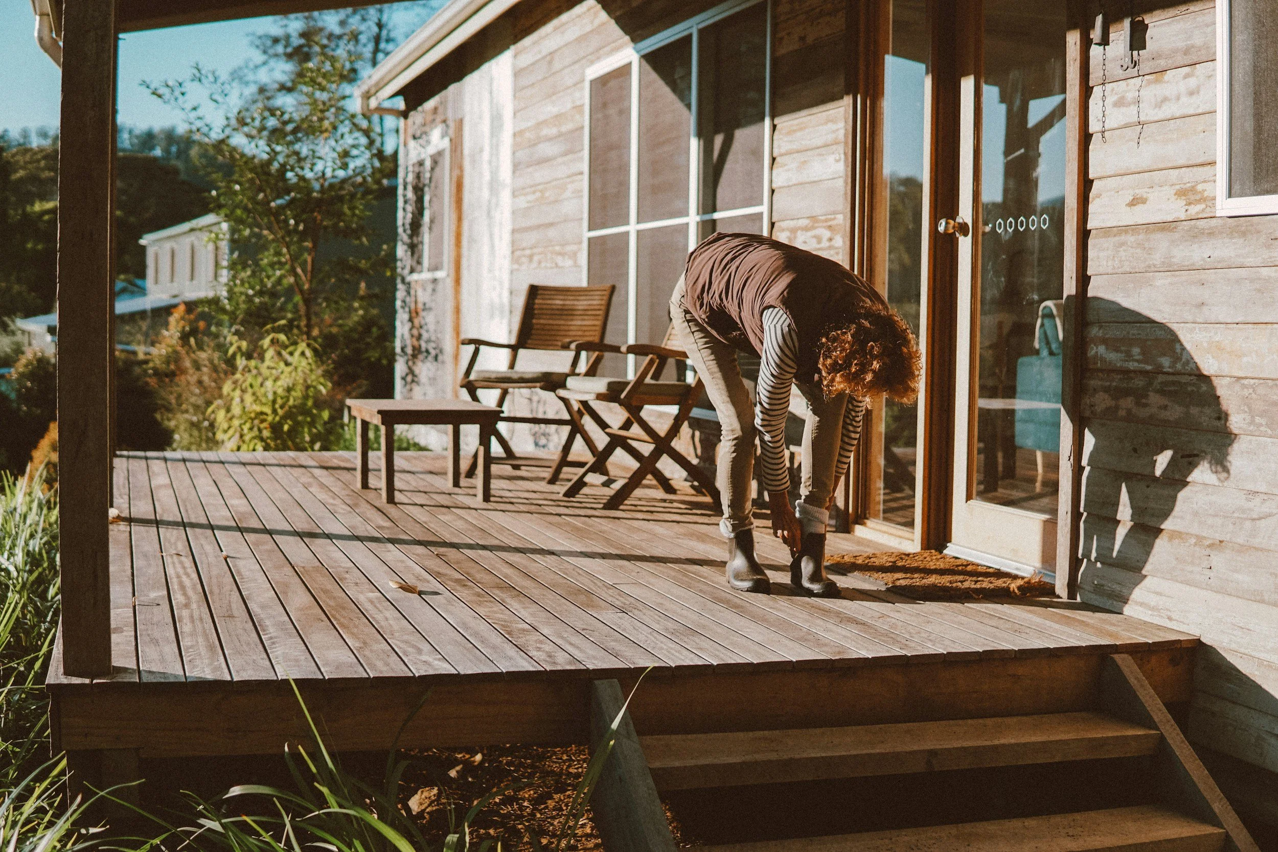 Person working on a wooden deck beside a home.
