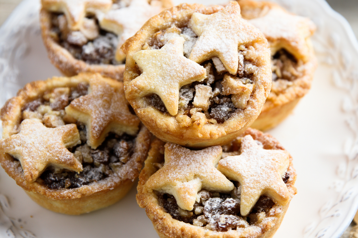 Star-shaped topped mince pies dusted with powdered sugar on a plate.