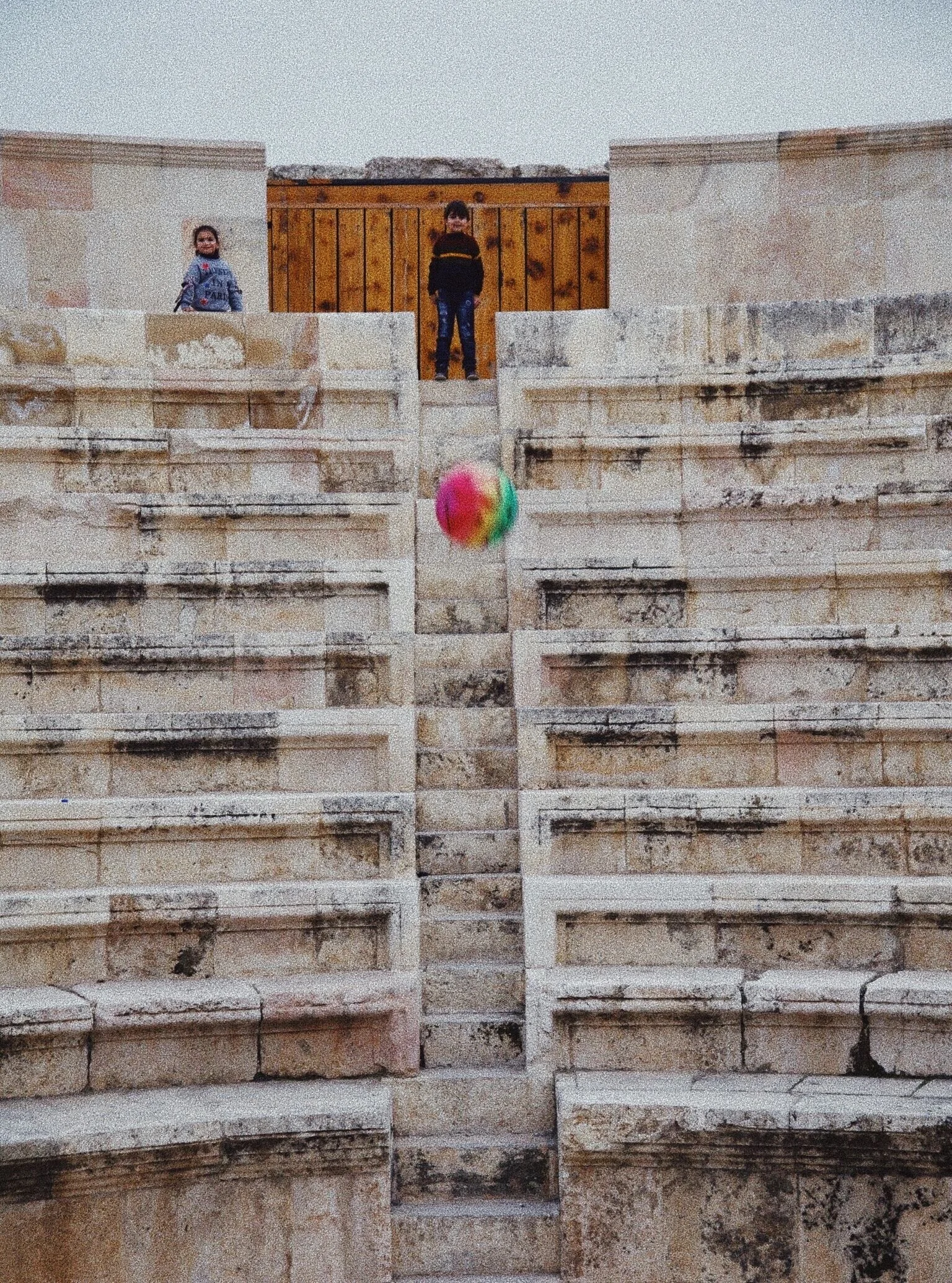 Children playing with a colorful ball on ancient stone steps