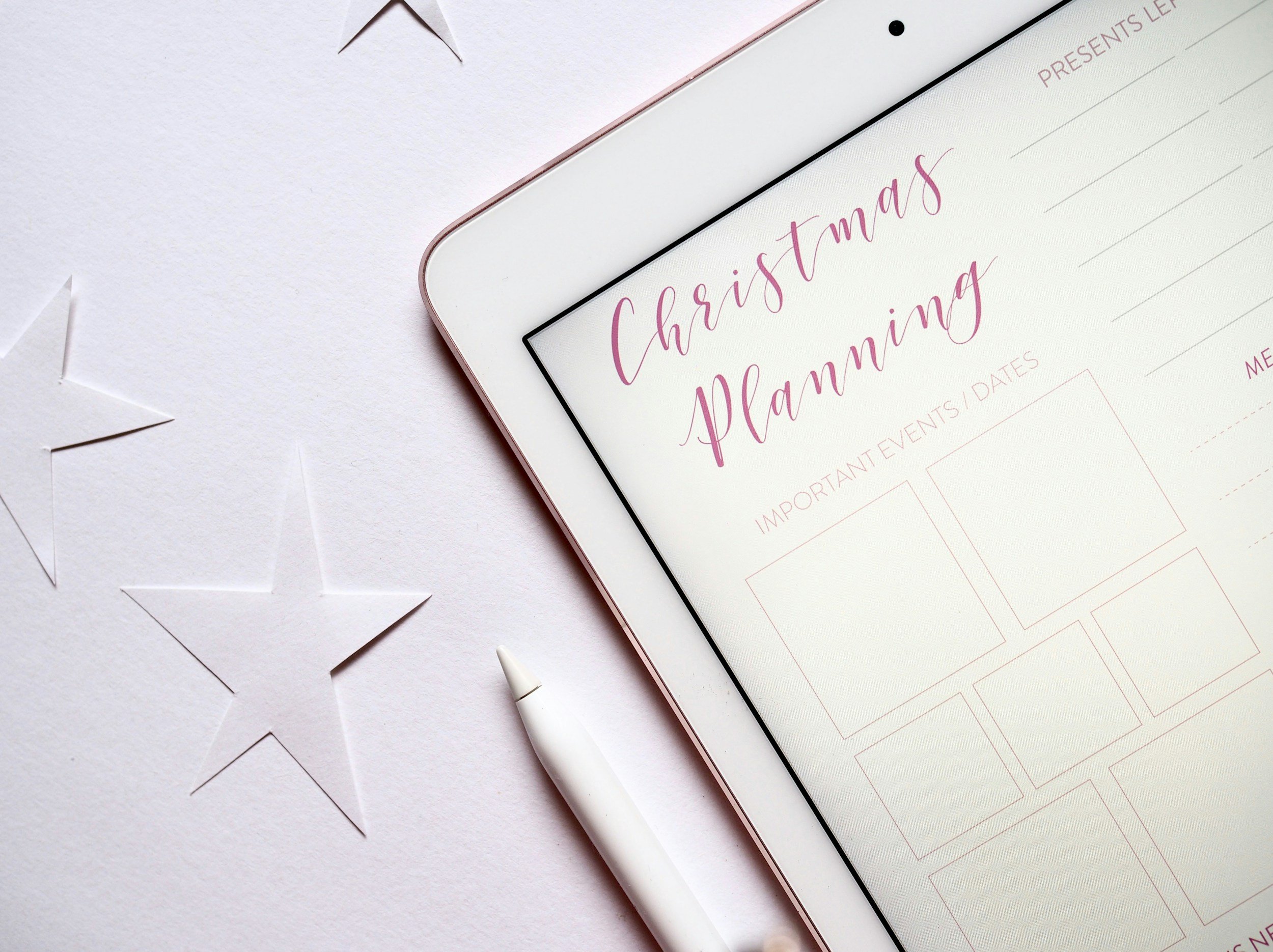 Christmas planning document on an iPad with an Apple Pencil and decorative stars, representing the Joy-Per-Dollar Rule, a Christmas budgeting strategy that helps Canadians save money while prioritizing meaningful gifts and holiday traditions.