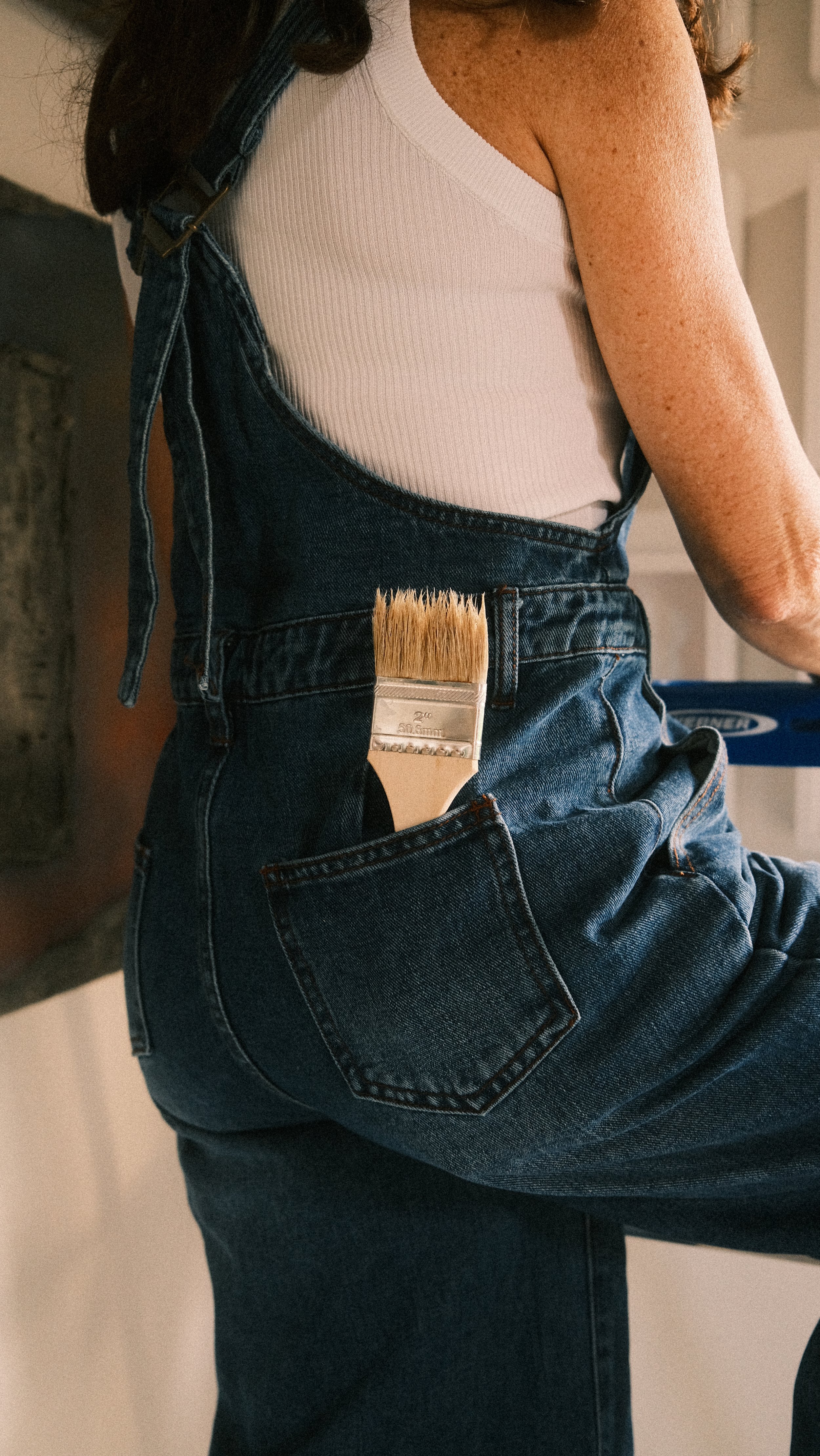 Detail of Sylvia Riquezes with a paintbrush in her back pocket.