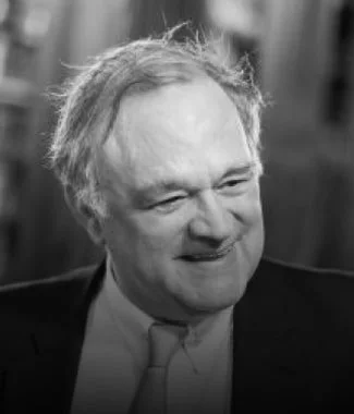 Close-up of a man with light-colored hair smiling, in black and white.