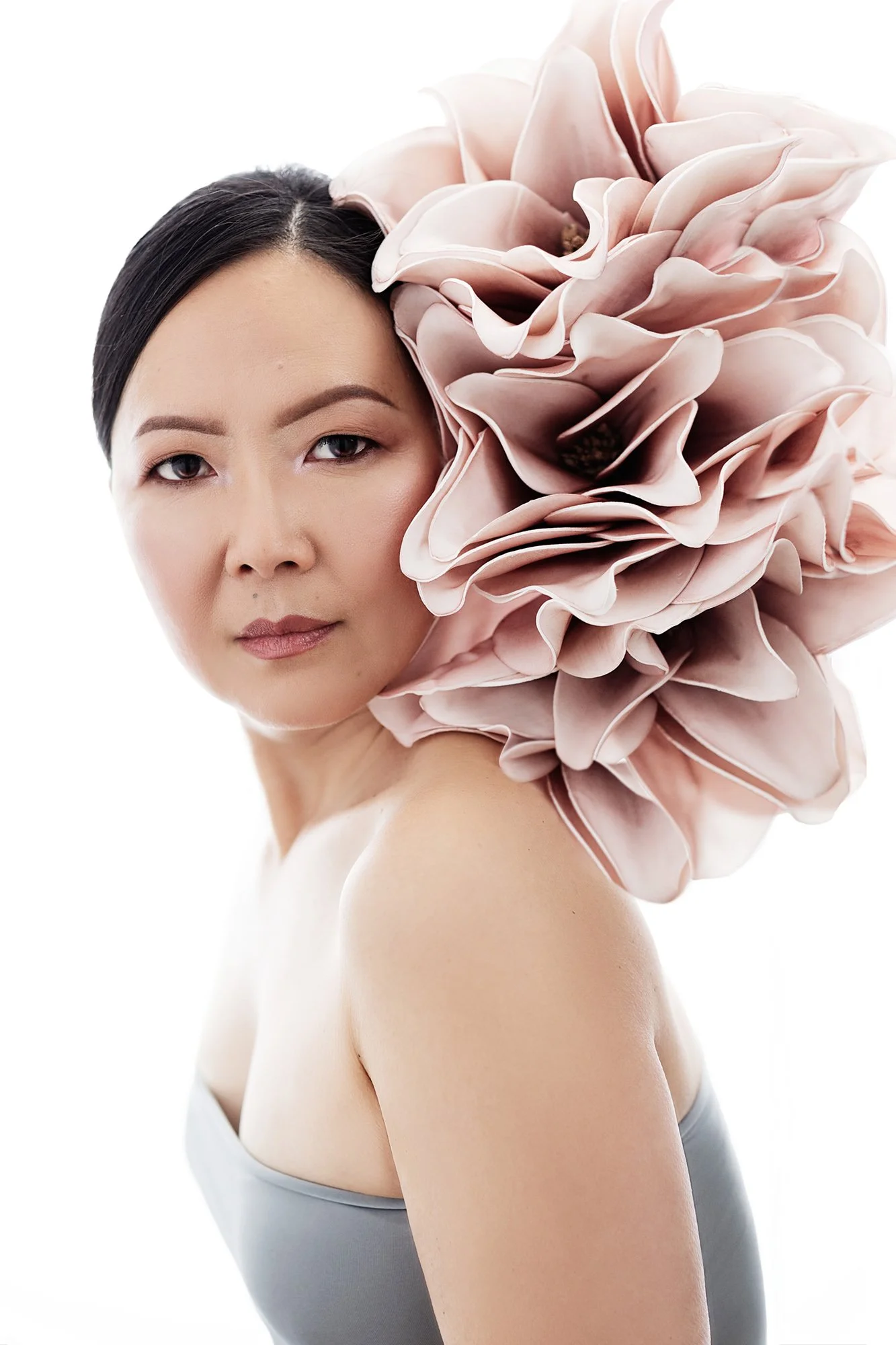 Hochwertiges Luxus-Portrait einer Frau über 40 mit einer übergroßen rosafarbenen Blüte — feine Portraitfotografie für Frauen in Innsbruck, Tirol, Österreich