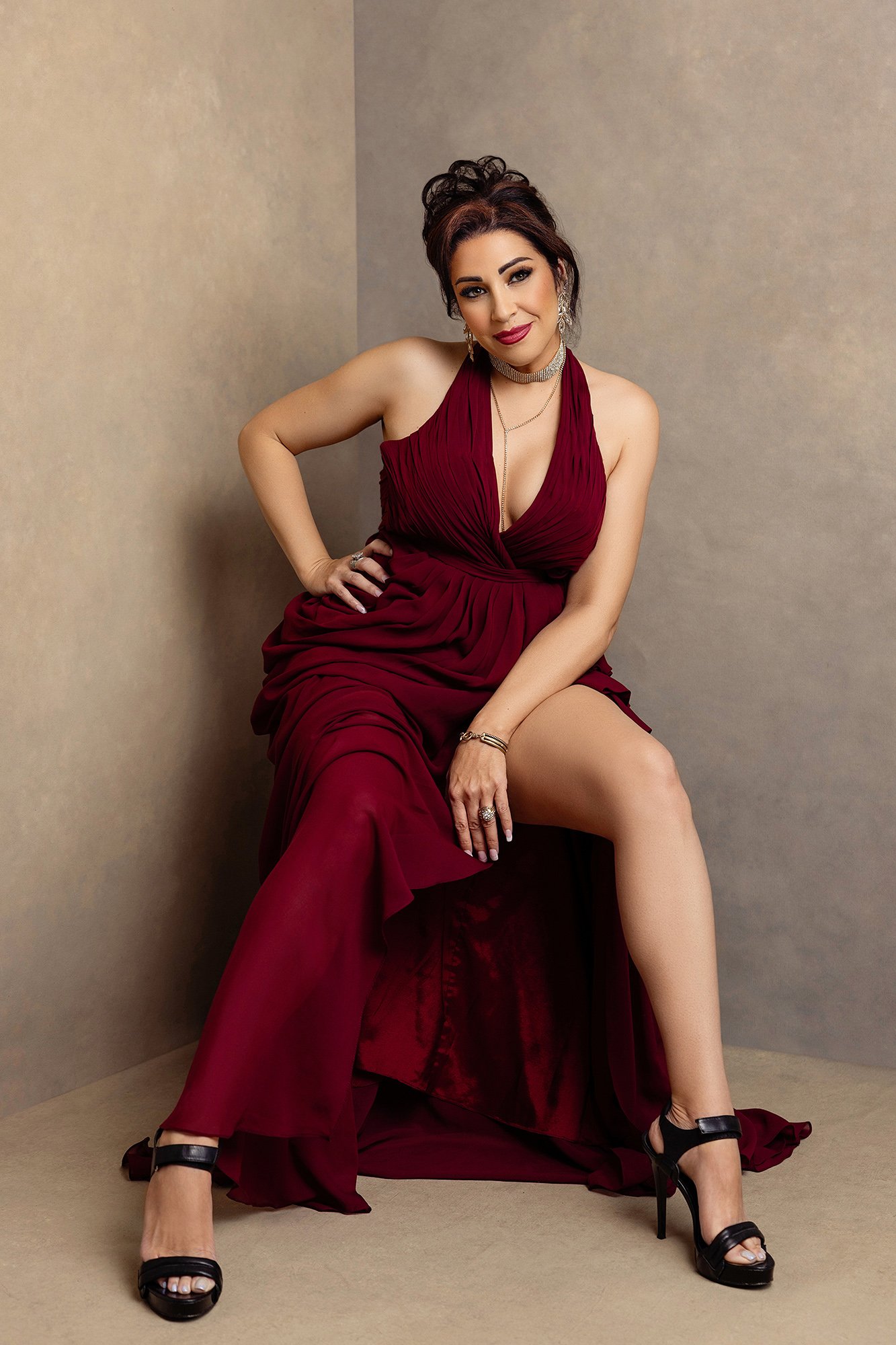 Elegant woman wearing a flowing red couture dress photographed during a luxury editorial portrait session in Austria.