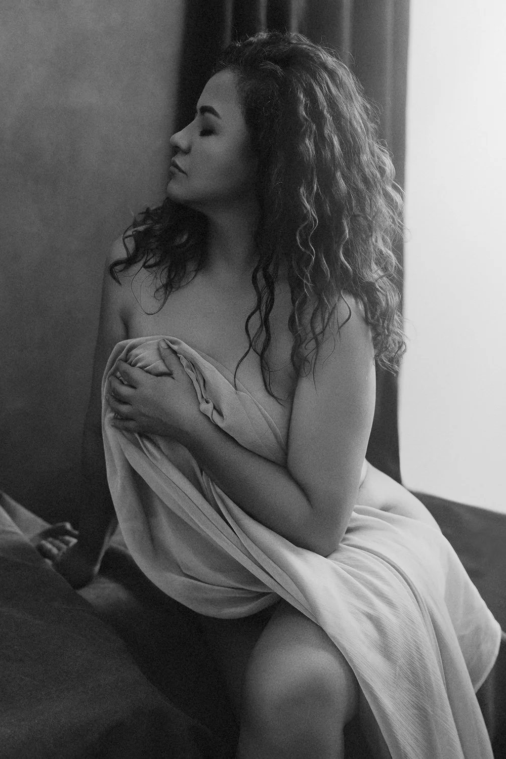 Fine art black and white intimate portrait of a woman holding draped fabric in window light — classical contemplative photography by Mayumi Acosta, Innsbruck Austria