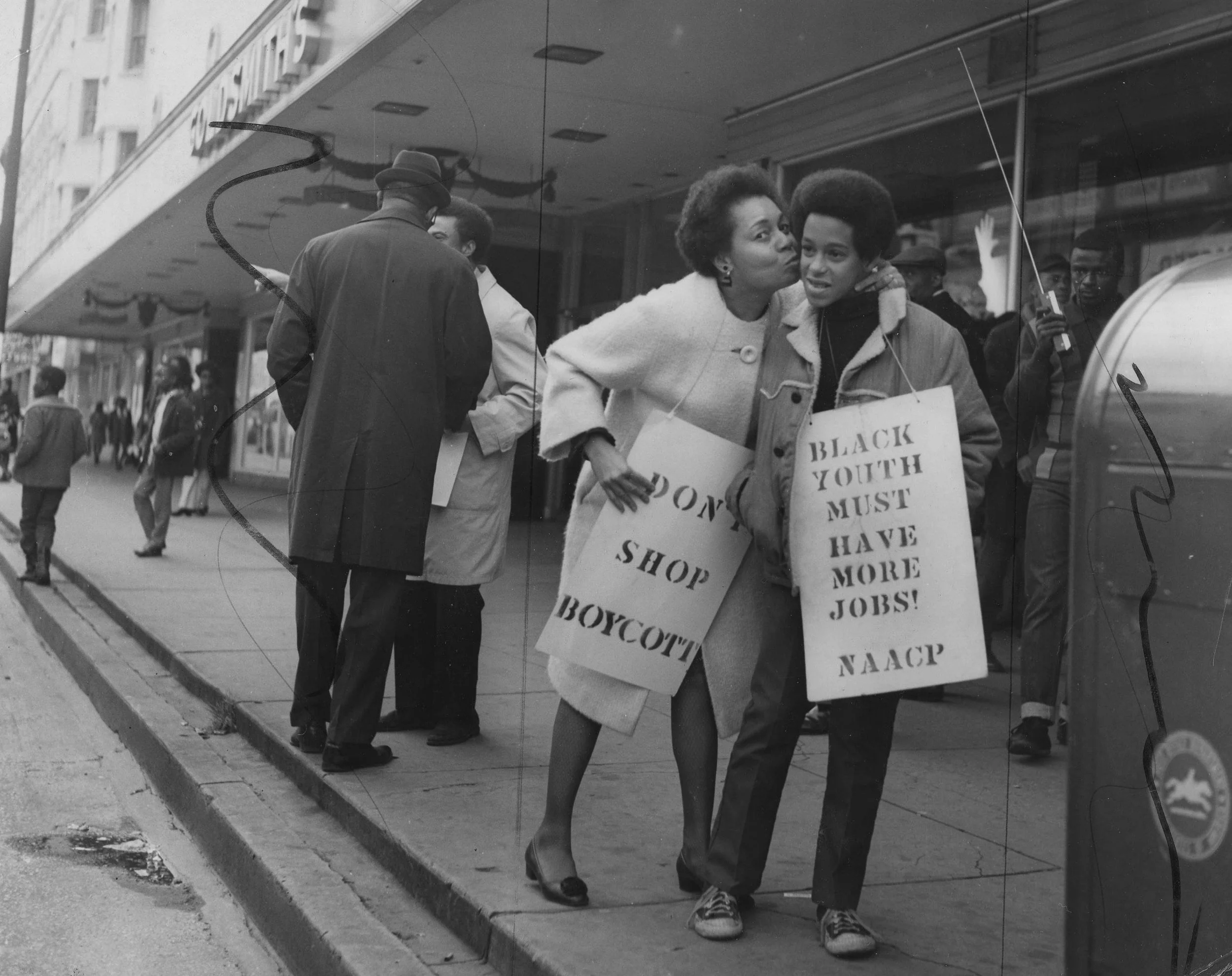A woman and a child hold protest signs outside of a Downtown Memphis department store.