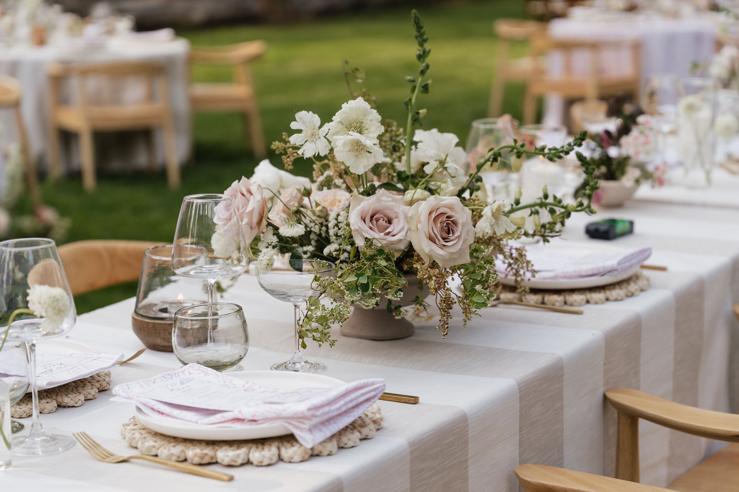 blush roses in a loose arrangement with a strip linen for a wedding reception