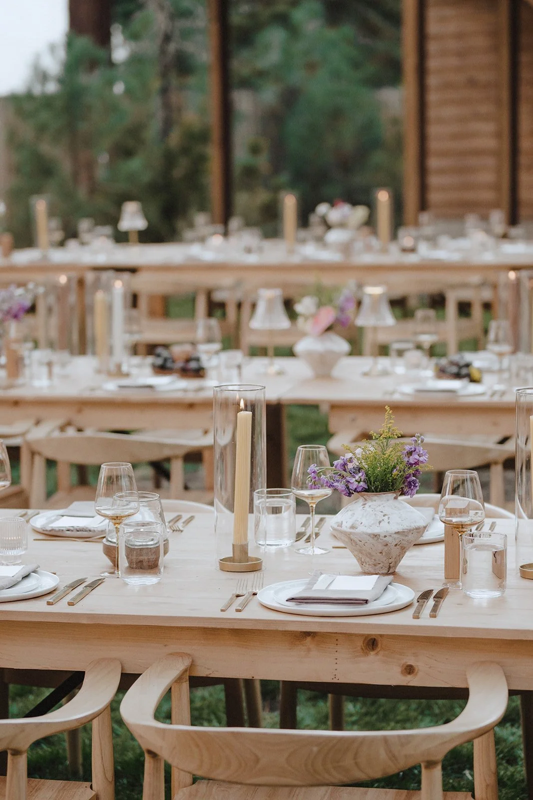 Wedding table with yellow candles, terracotta flower vases, light wood tables and chairs