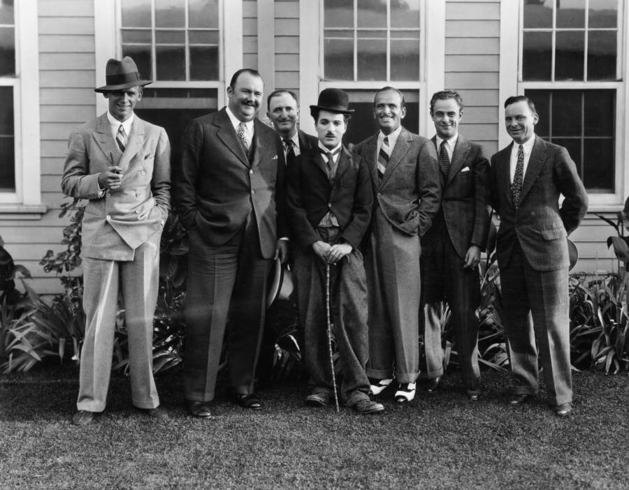 British actor and director Charles Chaplin (left) dressed as The Tramp, standing outdoors with actor Douglas Fairbanks Jr., bandleader Paul Whiteman, and actor Douglas Fairbanks Sr., 1925.