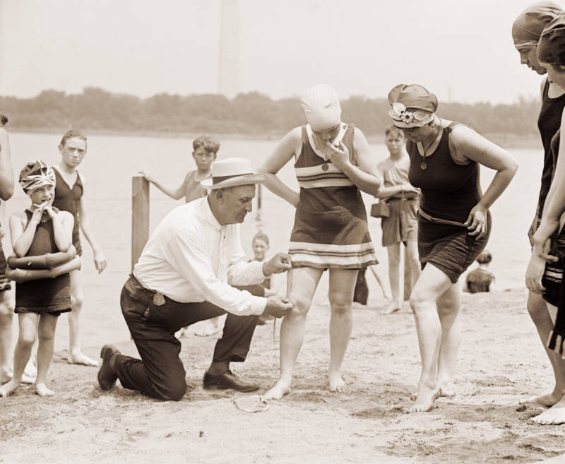 Woman having her swimsuit measured for length violations on a Washington D.C. beach in the 1920s.