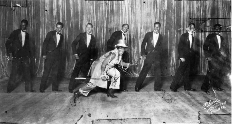 American blues and jazz vocalist Bessie Smith dances on stage in front of a line of men, Philadelphia, Pennsylvania, early twentieth century.