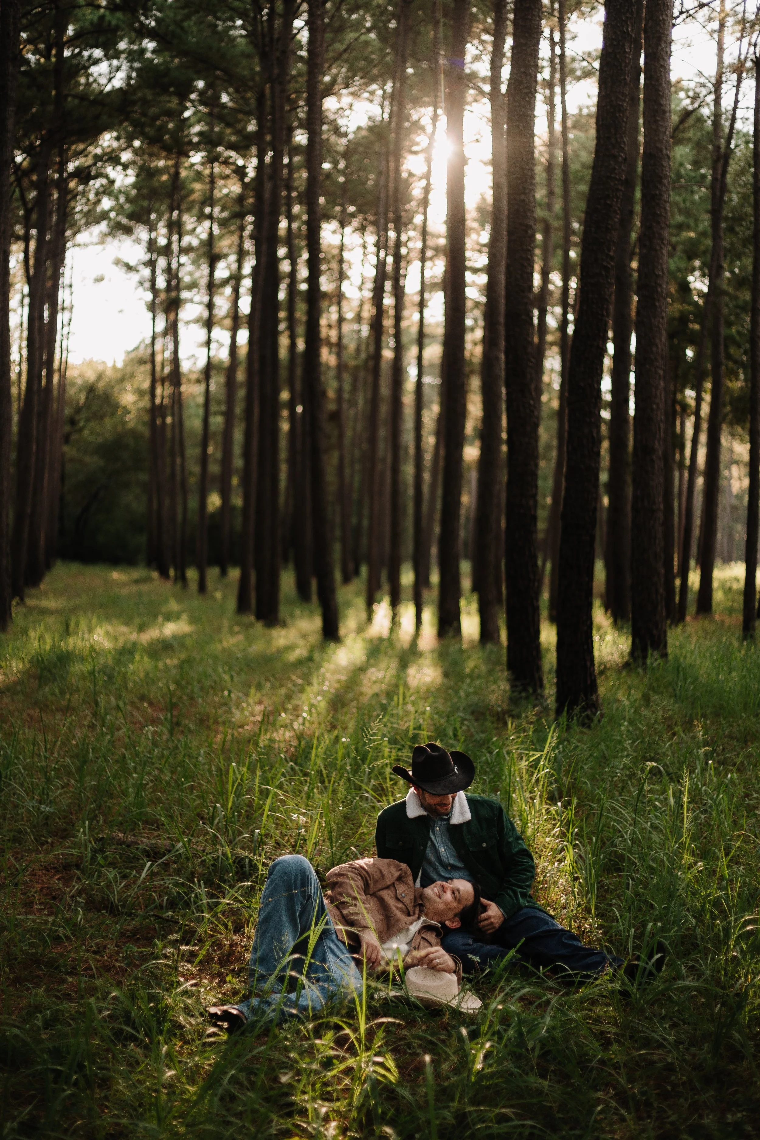 A gay couple laying in a forest during golden hour for an outdoor photoshoot in Conroe, Texas.