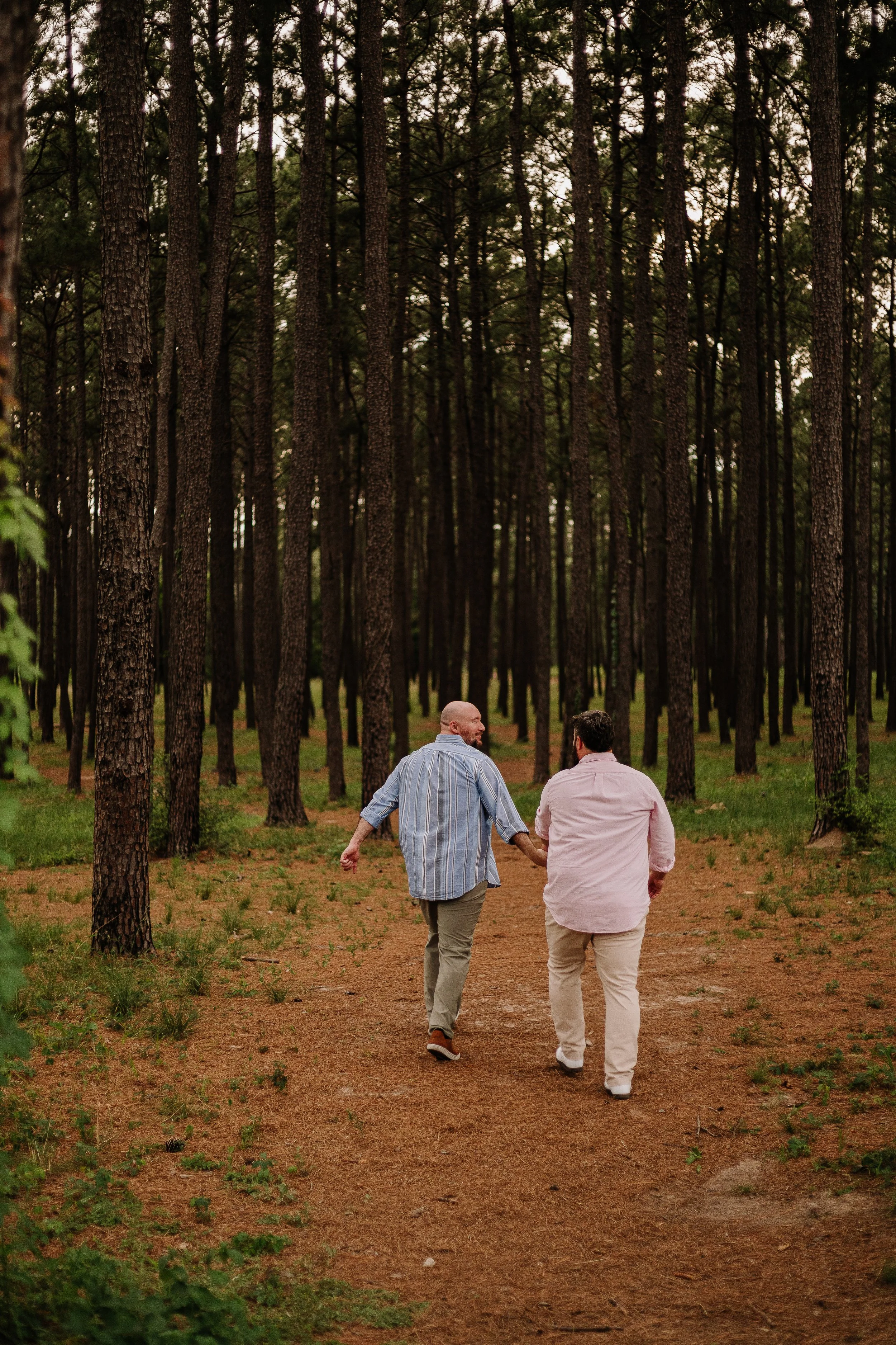A gay couple holding hands, walking through the woods happily in Conroe, Texas