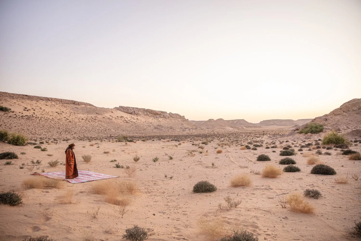 Dressed in a winter robe, a Yemeni Bedouin man prepares for sunset prayers in the Empty Quarter Desert. Yemen.