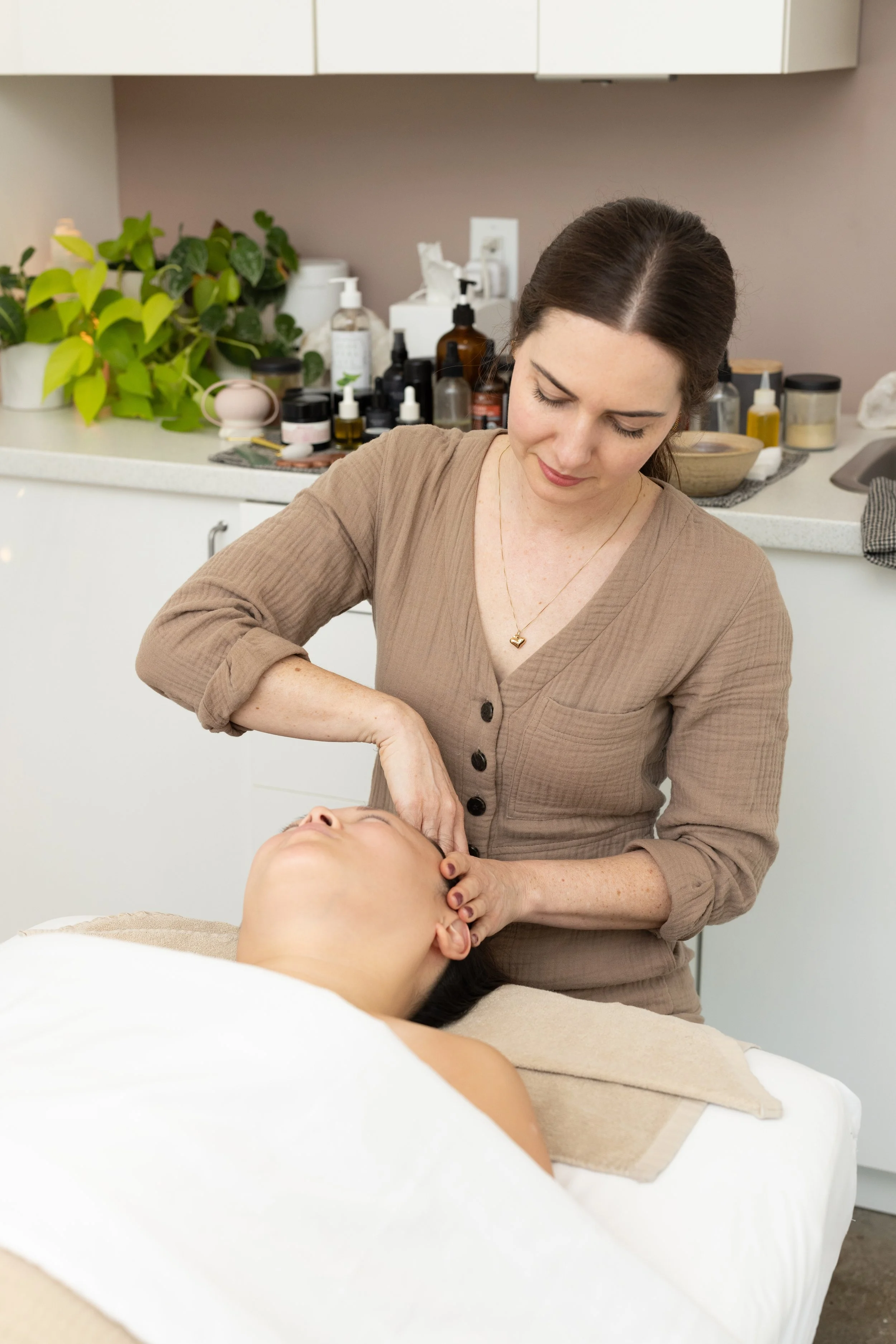 Woman receiving a facial massage from esthetician in skincare clinic.