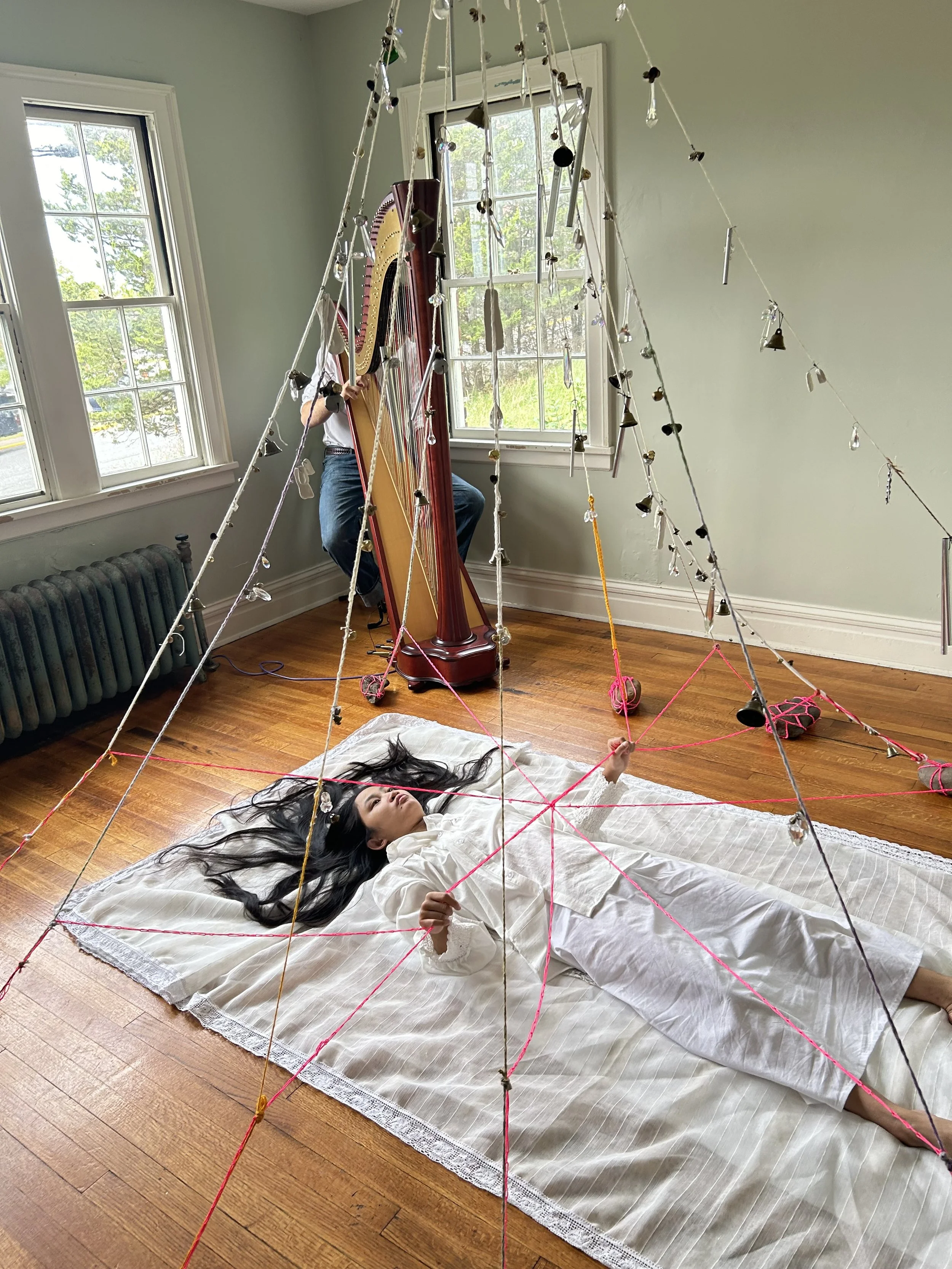 "Out of Body" performed by Faye Ross, 2024, bells, crystals, found objects, porcelain, construction string, cotton string, rocks, fabric, Malachi Purcell accompanying on harp at Tanja Grunert Gallery, Hudson, NY