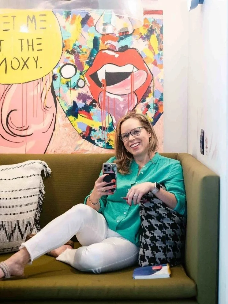 Kristin in green top sitting on a couch against a colorful wal in DC