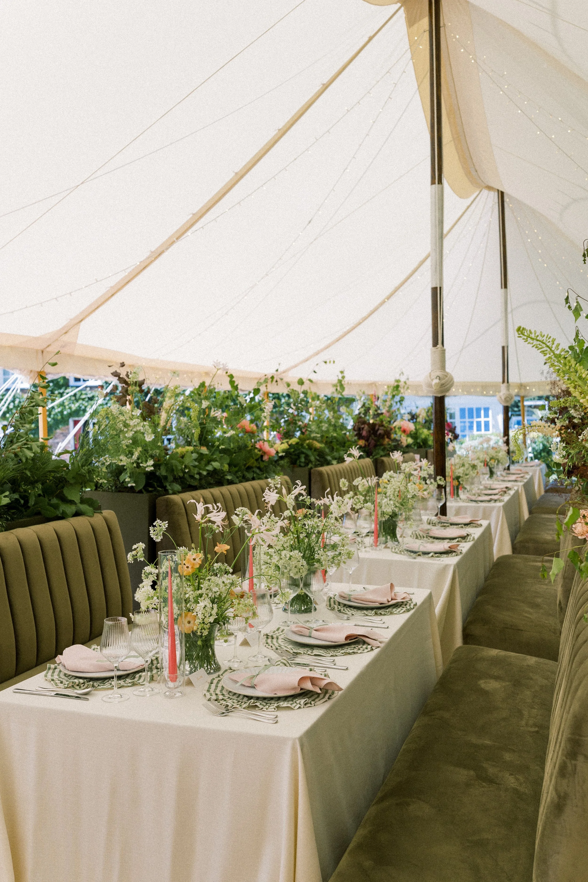 Long marquee banquet table with large floral planter decor and green sofa seating