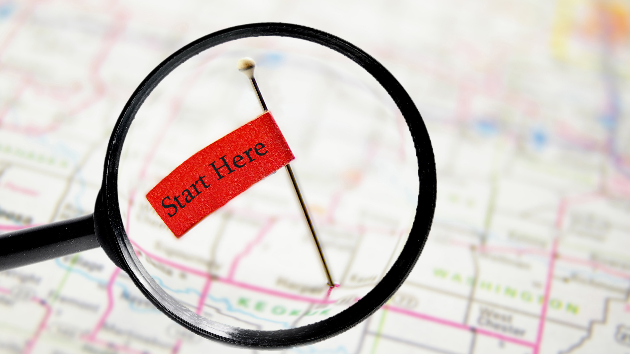 magnifying glass over map with start here flag