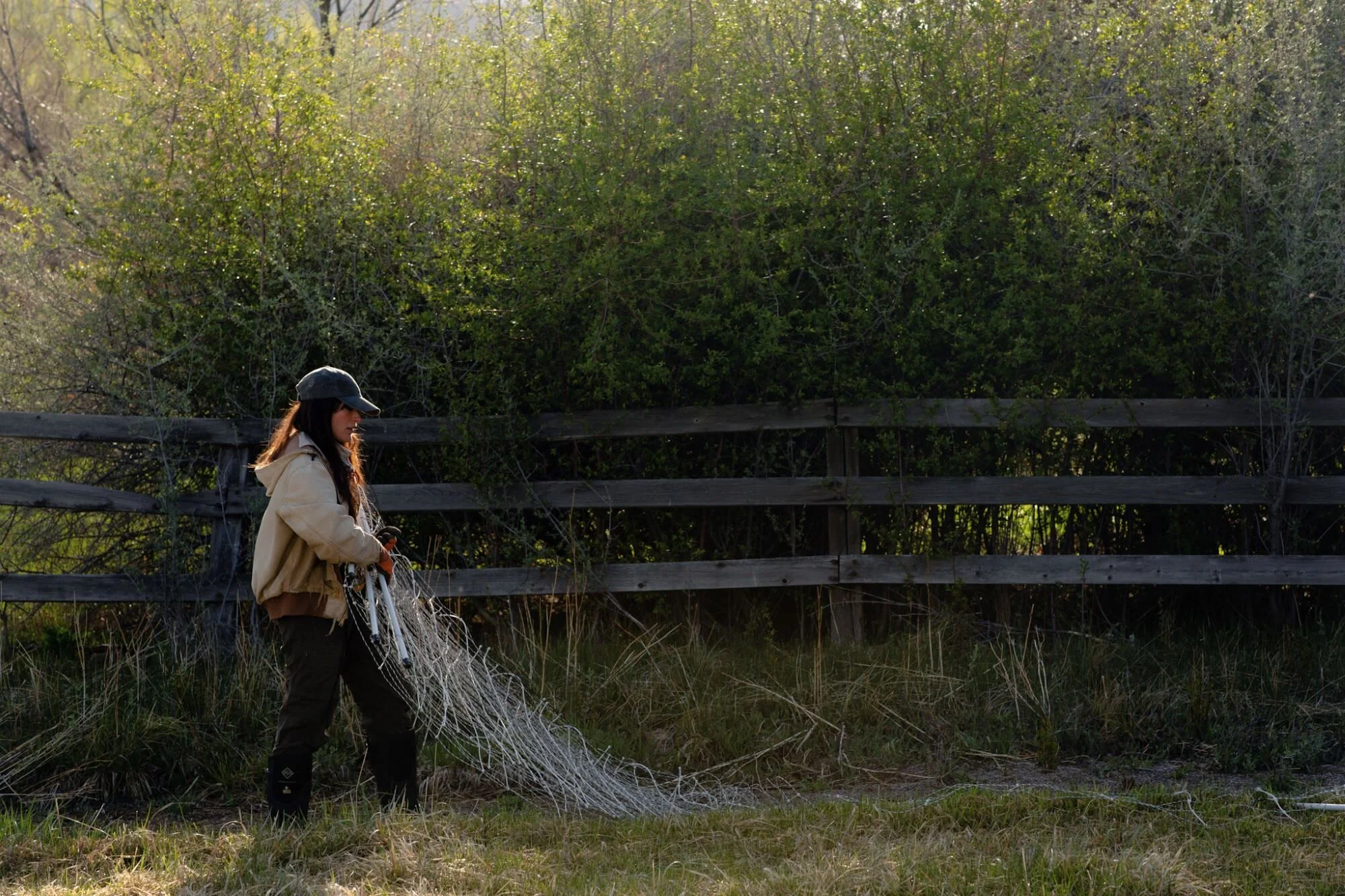 woman farmer lays electric fence out in pasture.jpg