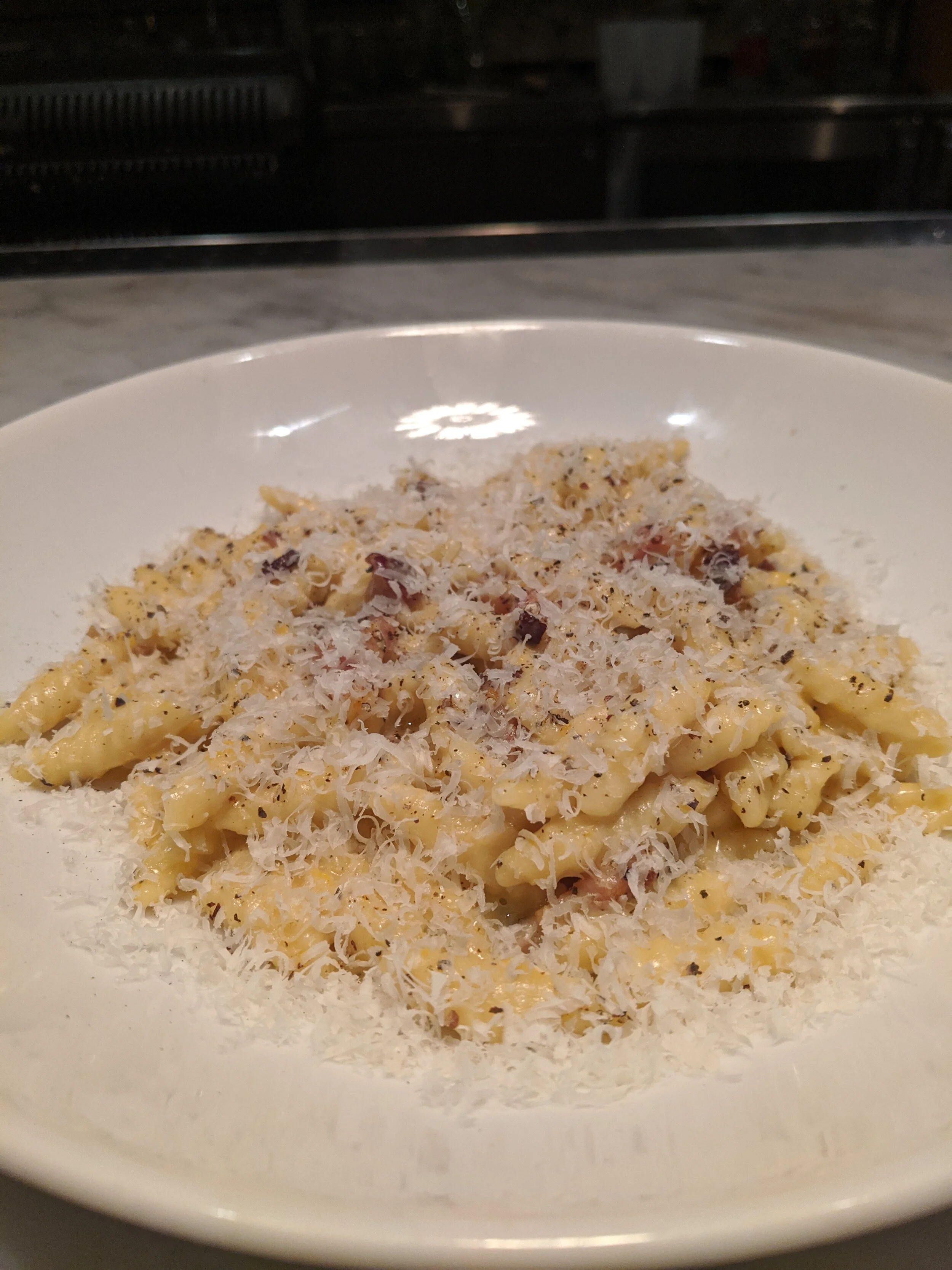 Plate of cooked pasta topped with grated cheese and black pepper.