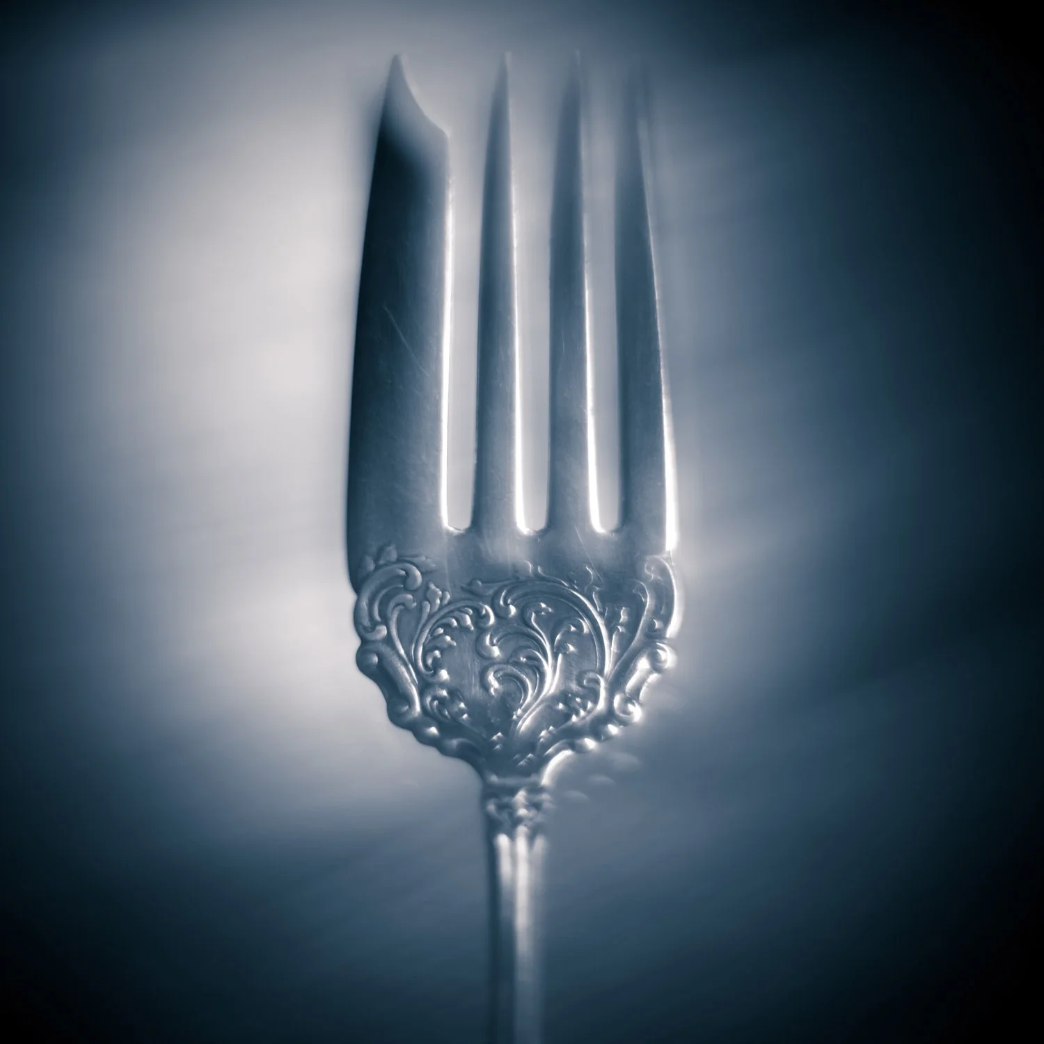 A silver fork photographed by Mark Robert Halper in luminous blue and silver light.