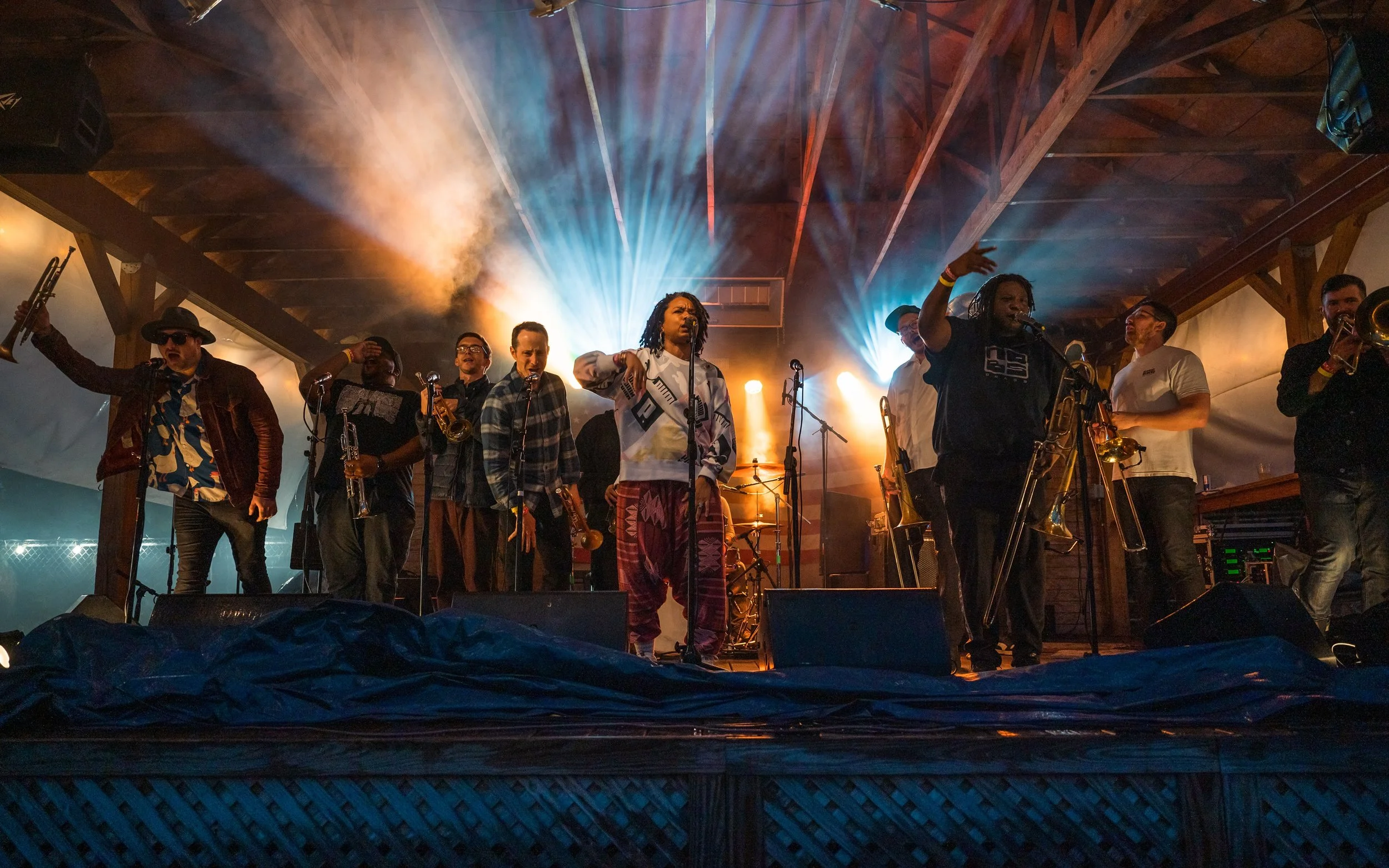 A live band performing on stage with multiple musicians and singers under colorful stage lights.