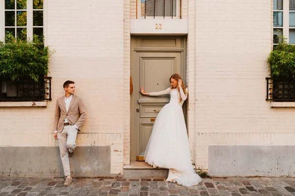 Un homme et une femme habillés pour un mariage devant une porte d'immeuble