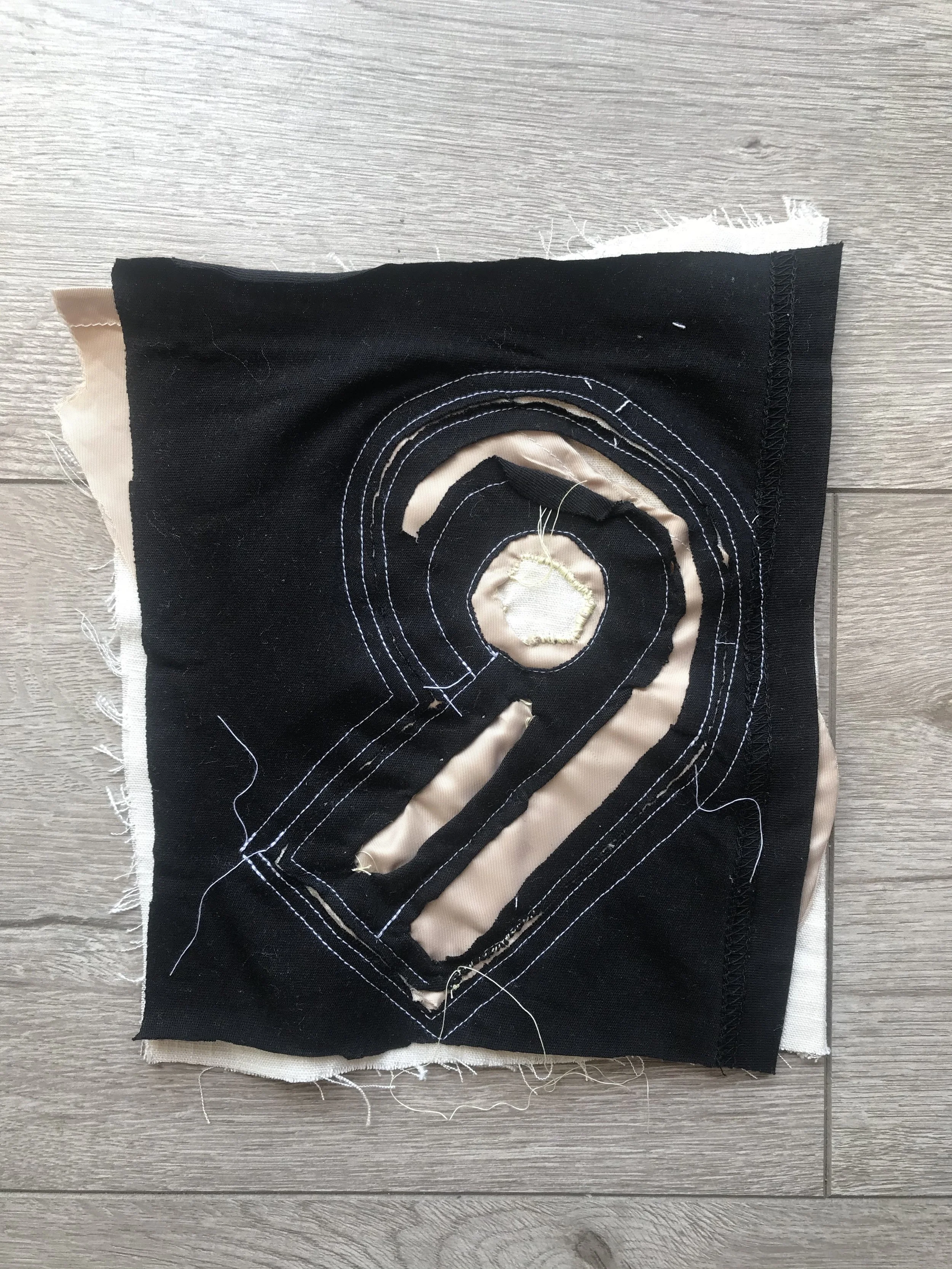 Machine stitched design onto 3 layers of fabric (in order to secure placement/ stay stitches) sample includes: black Poly-cotton knit, peach woven Sateen, woven linen bottom layer : To improve this sample in the future, I would like to make all stay