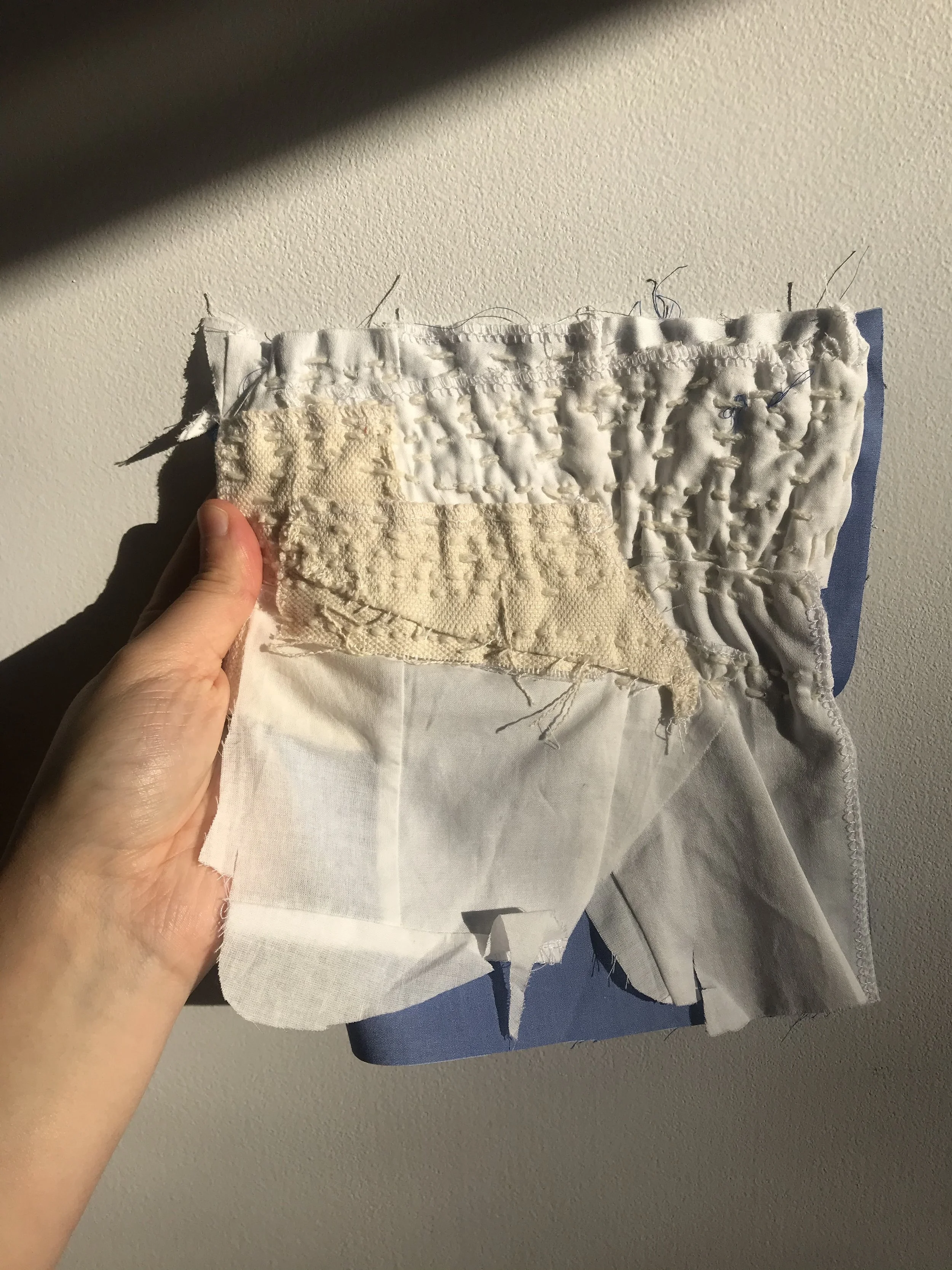 Boro Technique sample is made up of heavy weight canvas, cotton remnants and blue polyester backing. Joined on machine initially to secure the various pieces in place. The running stitch (Polyester yarn was used) was applied after the machine stitch.