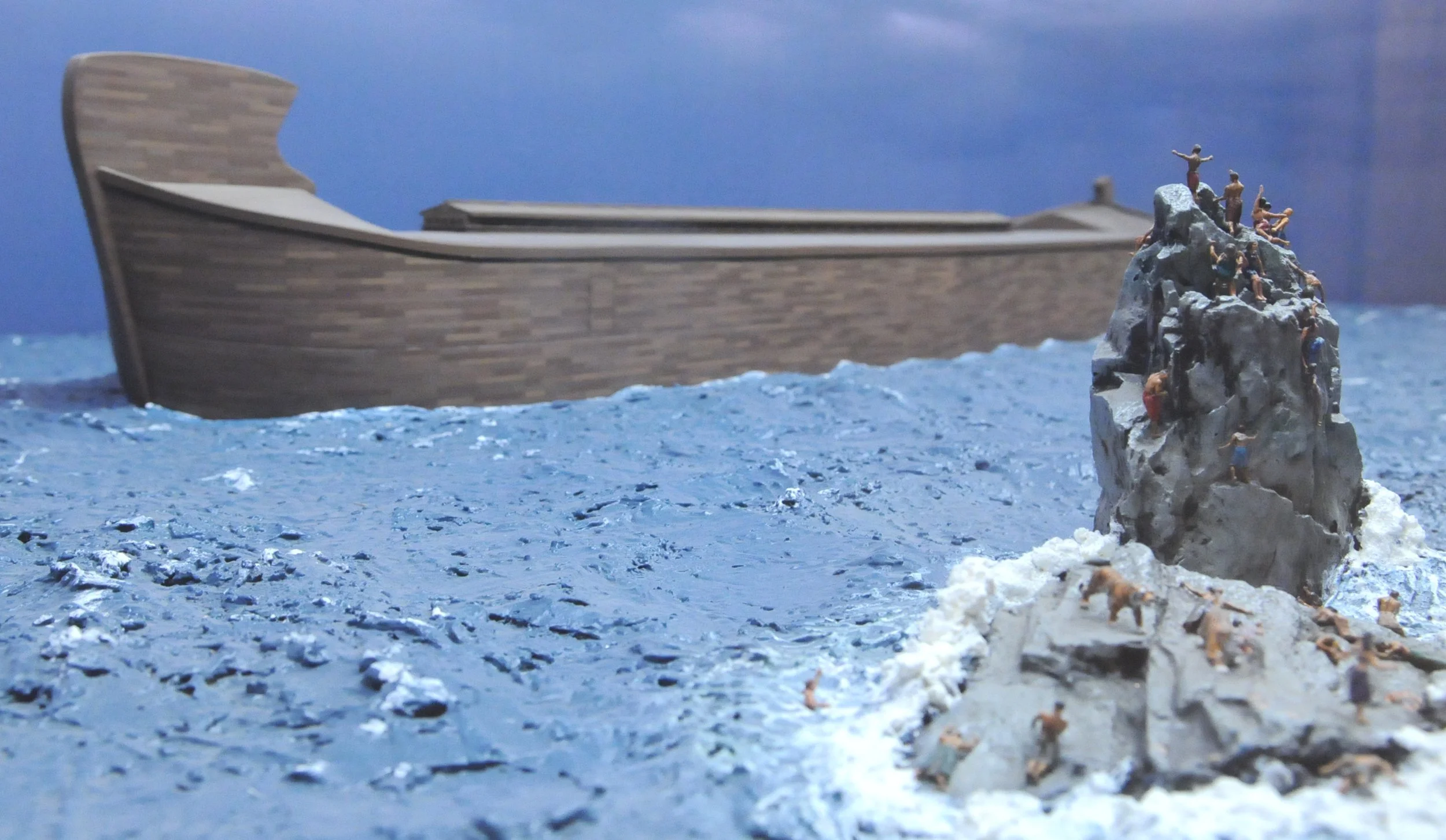 Diorama from the Genesis Creation Museum depicting a model of Noah's Ark with several small figures on a rock looking at it.