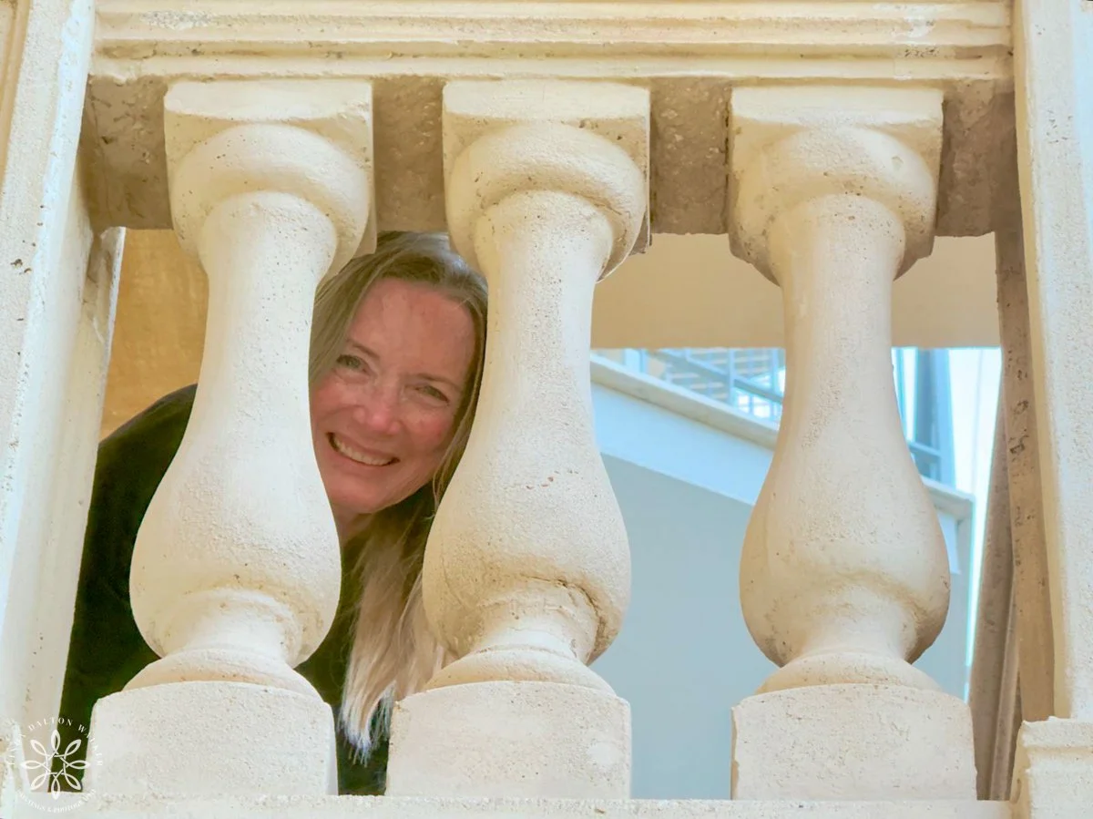 Author leaning through balcony poles in Italy.