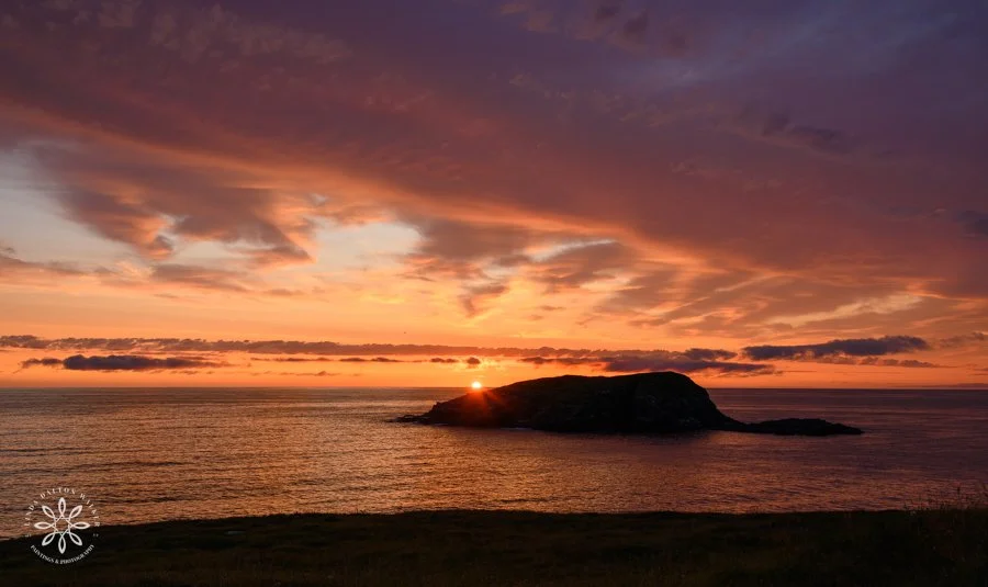 Vibrant orange sunrise with a rocky island in the water, Newfoundland, Canada