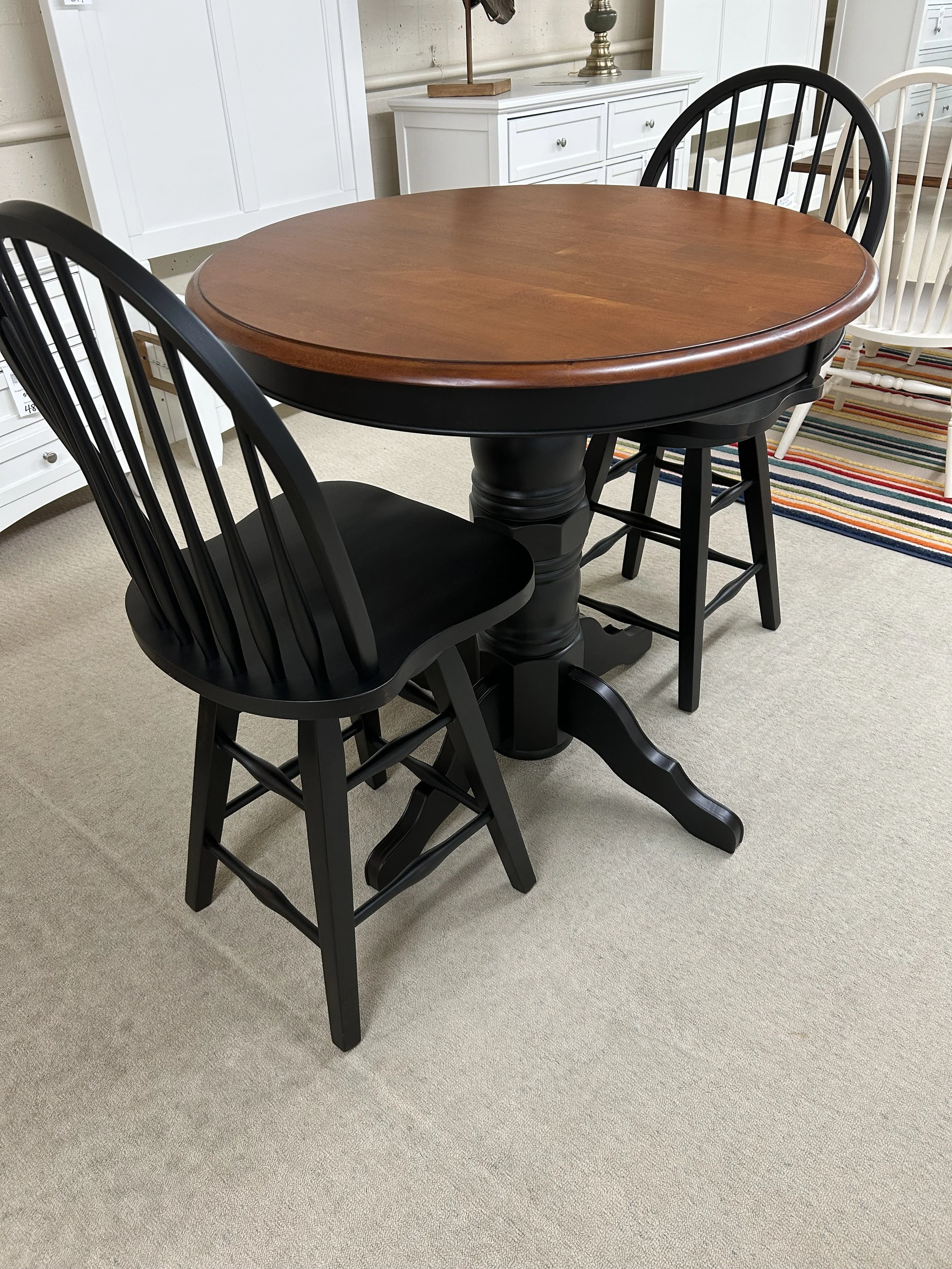 36” W x 36” H round-top  pub table in two tone finish with two 24” swivel barstools in black finish by TEI