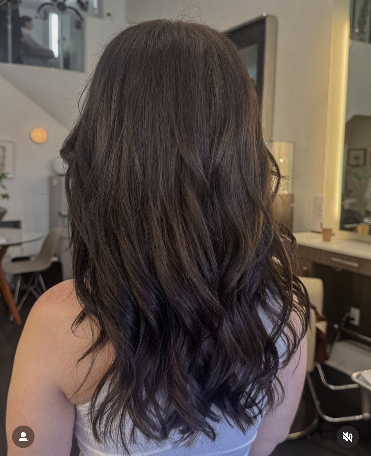Woman with long, wavy, dark brown hair in an indoor setting.