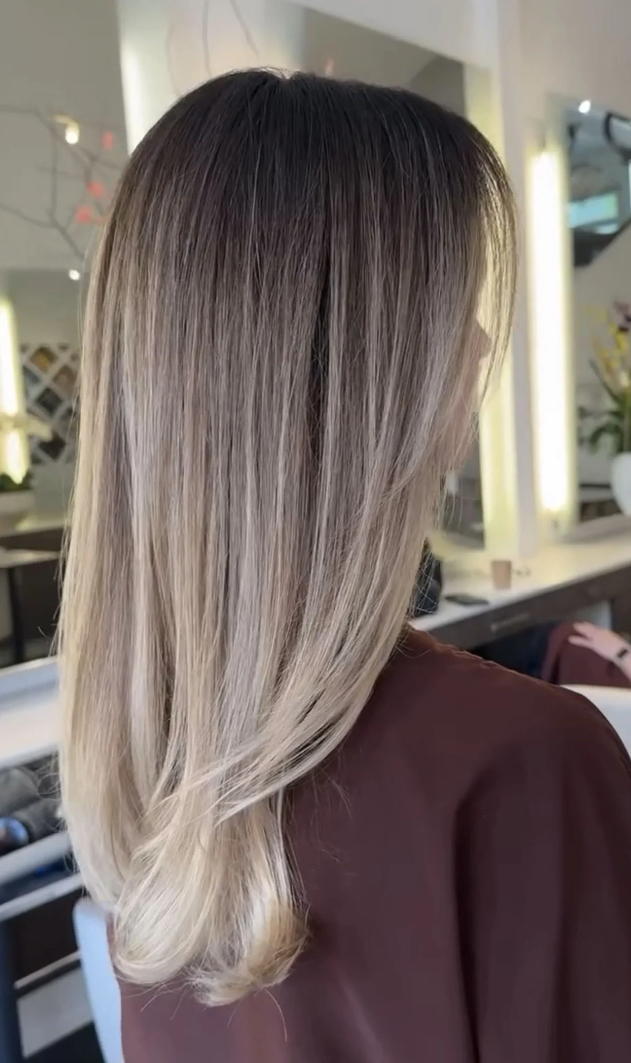 Side view of a woman with long, straight, ombre blonde hair in a salon.