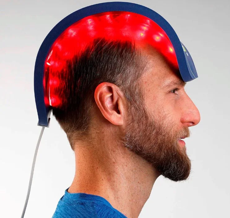 A man wearing a helmet with a red LED light panel on the top, which appears to emit red light.