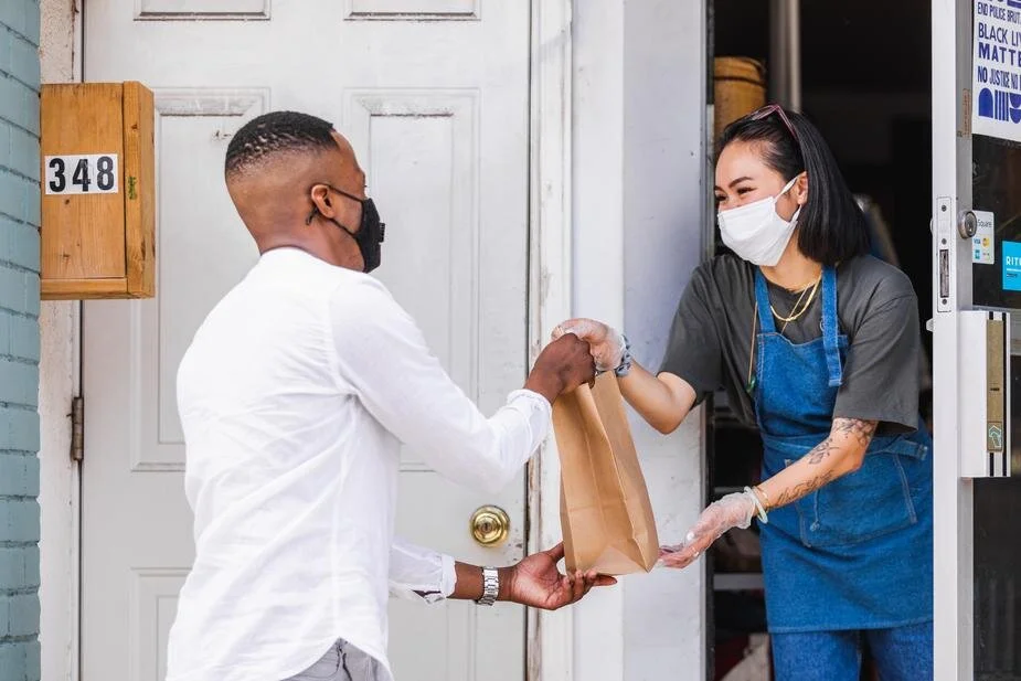 two-people-exchange-groceries-at-curbside.jpg