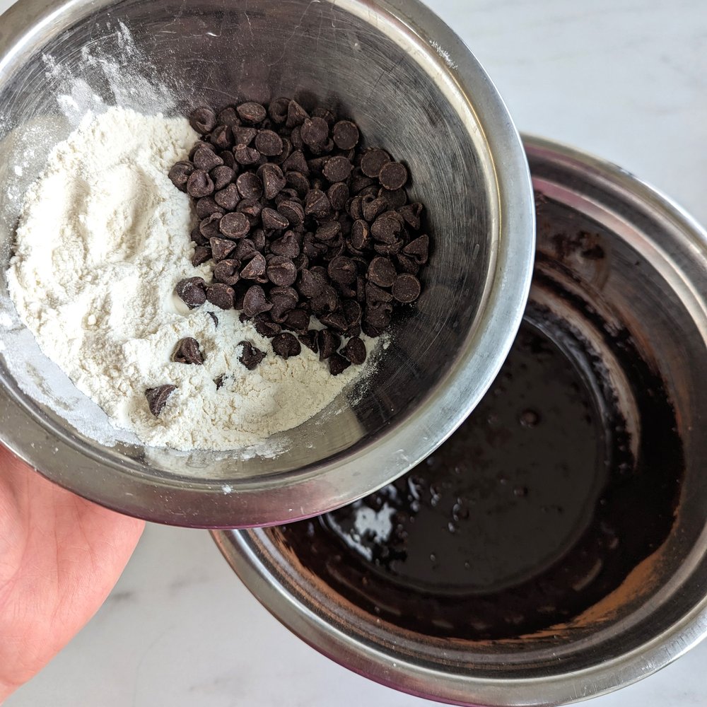 adding chocolate chips and flour to brownie batter.jpg