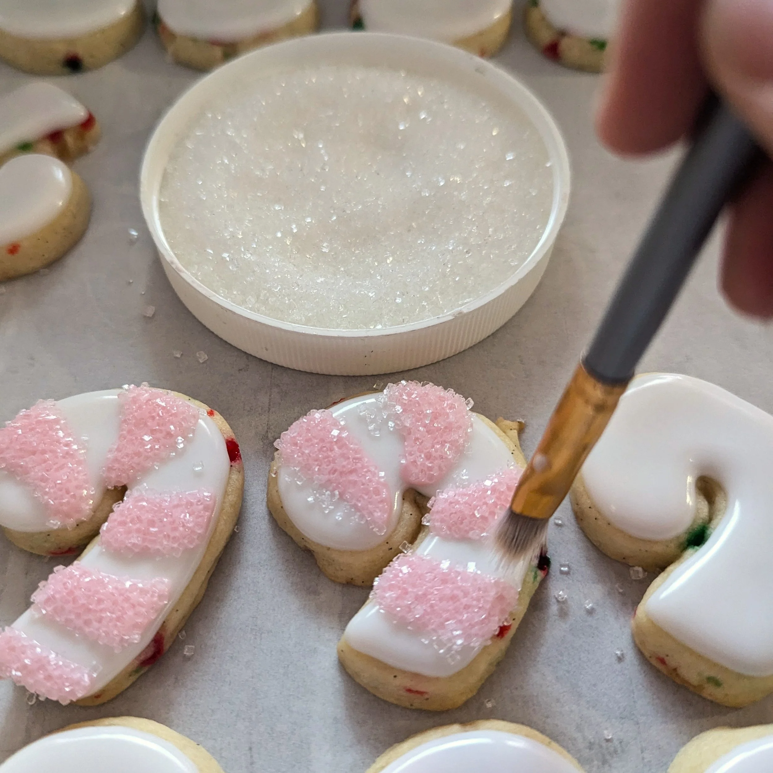 dusting sanding sugar off candy cane cookies.jpg