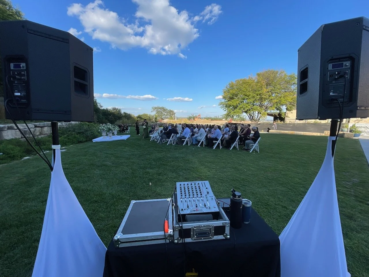 DJ booth and speakers set up for an outdoor wedding ceremony in the gardens at Lauritzen Gardens in Omaha
