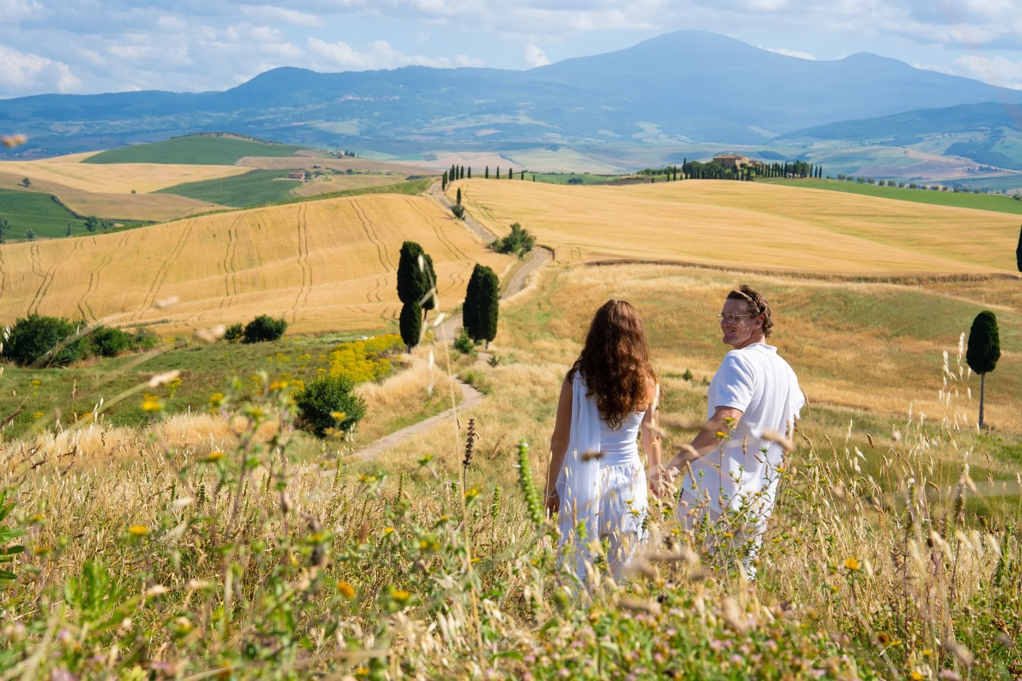 Rhett and Claire walking through golden fields in the Val d'Orcia, Tuscany