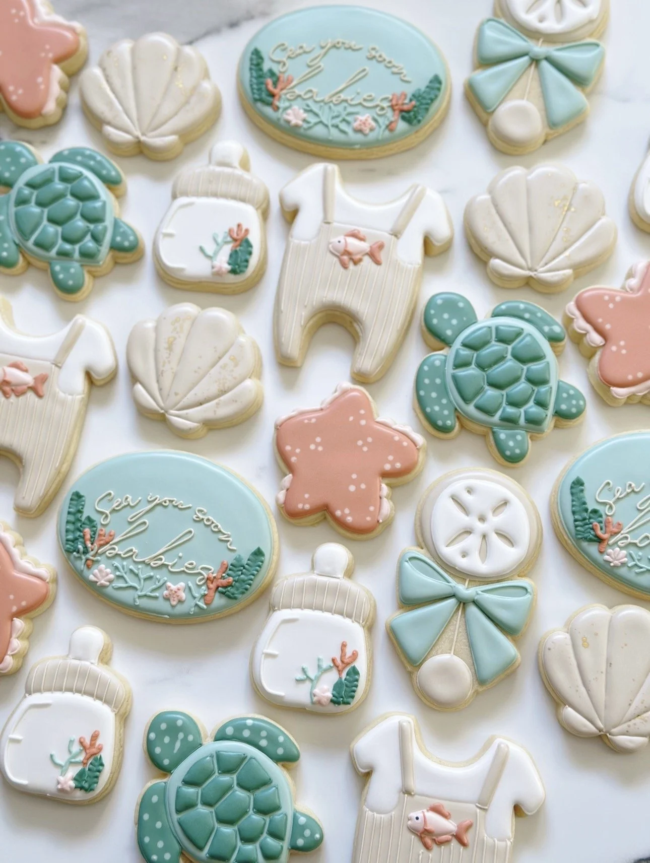 Decorative cookies with ocean and beach themes, including shells, turtles, starfish, a pineapple, and a message that reads 'Sea you soon, beach'.