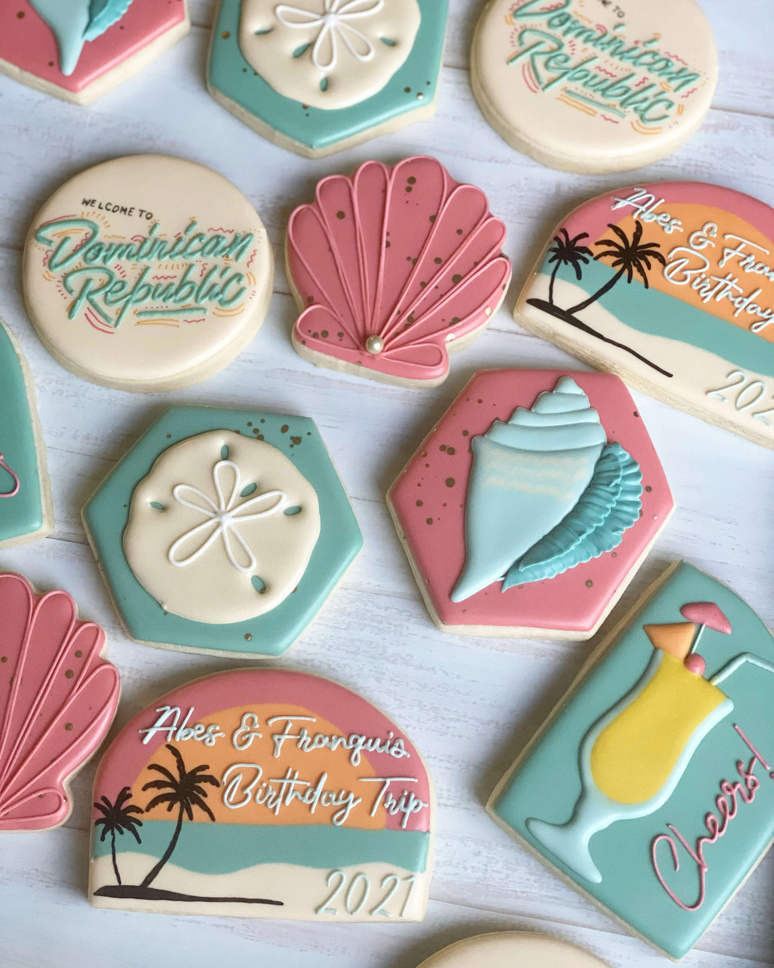 Collection of decorated cookies with tropical and travel themes, including a palm tree, a seashell, a beach and sunset scene, and text references to a birthday trip to the Dominican Republic in 2021.