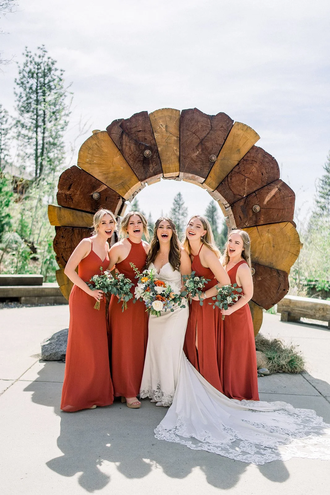 Bride and her bridesmaids in orange dresses smiling with bouquets, groveland ca