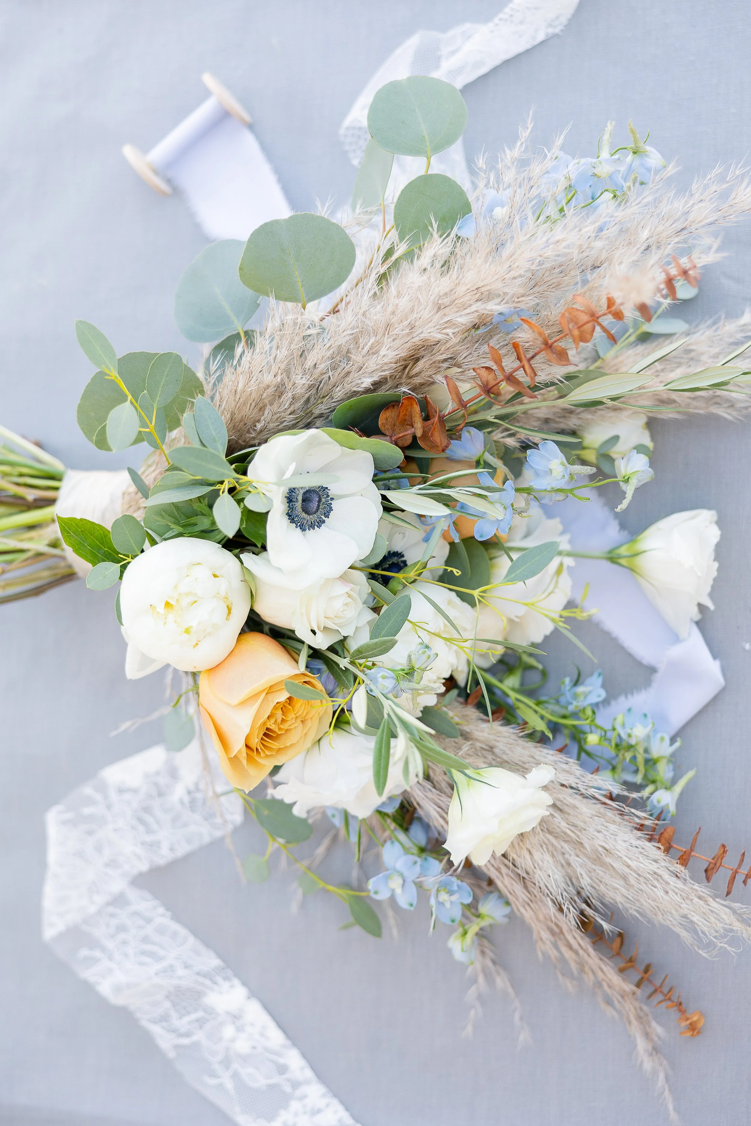 bridal bouquet made of pampas, anemone, peony, and toffee rose laying on ribbon, tuolumne county 