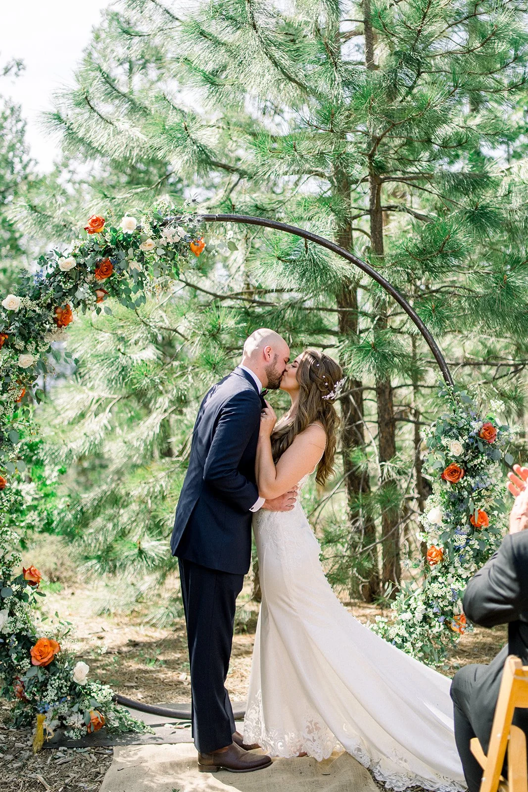 Bride and groom kissing in front of a floral arch, groveland ca