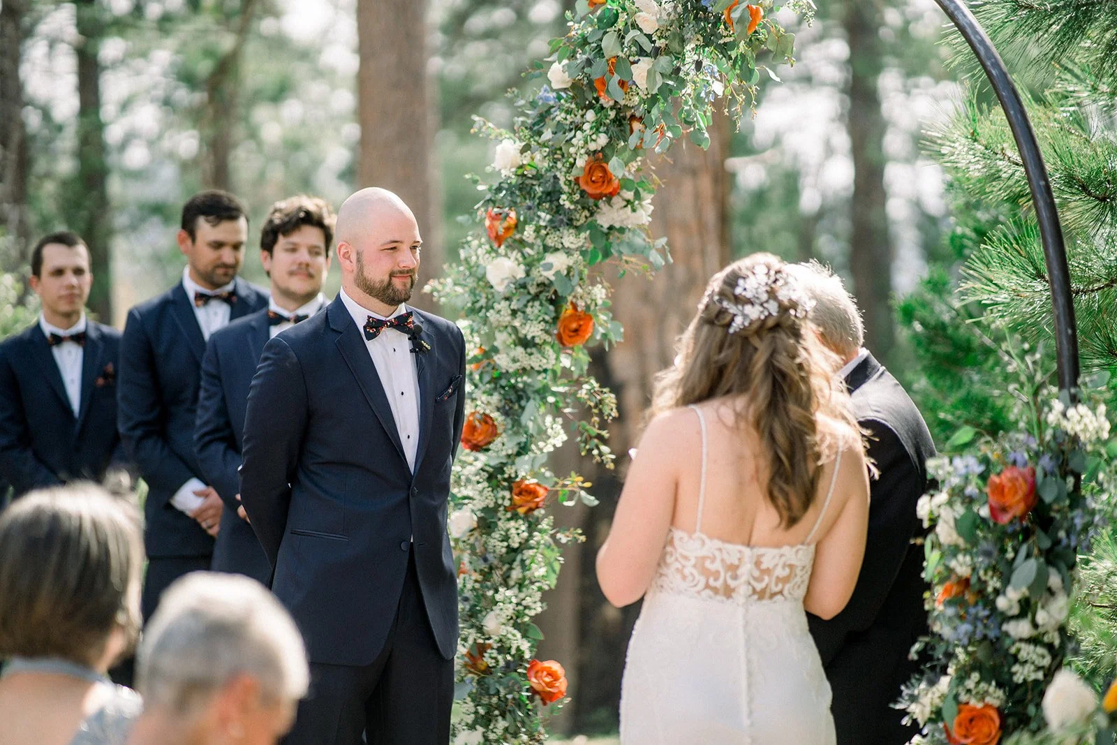 Couple standing in front of round floral arch saying vows, rushcreek lodge