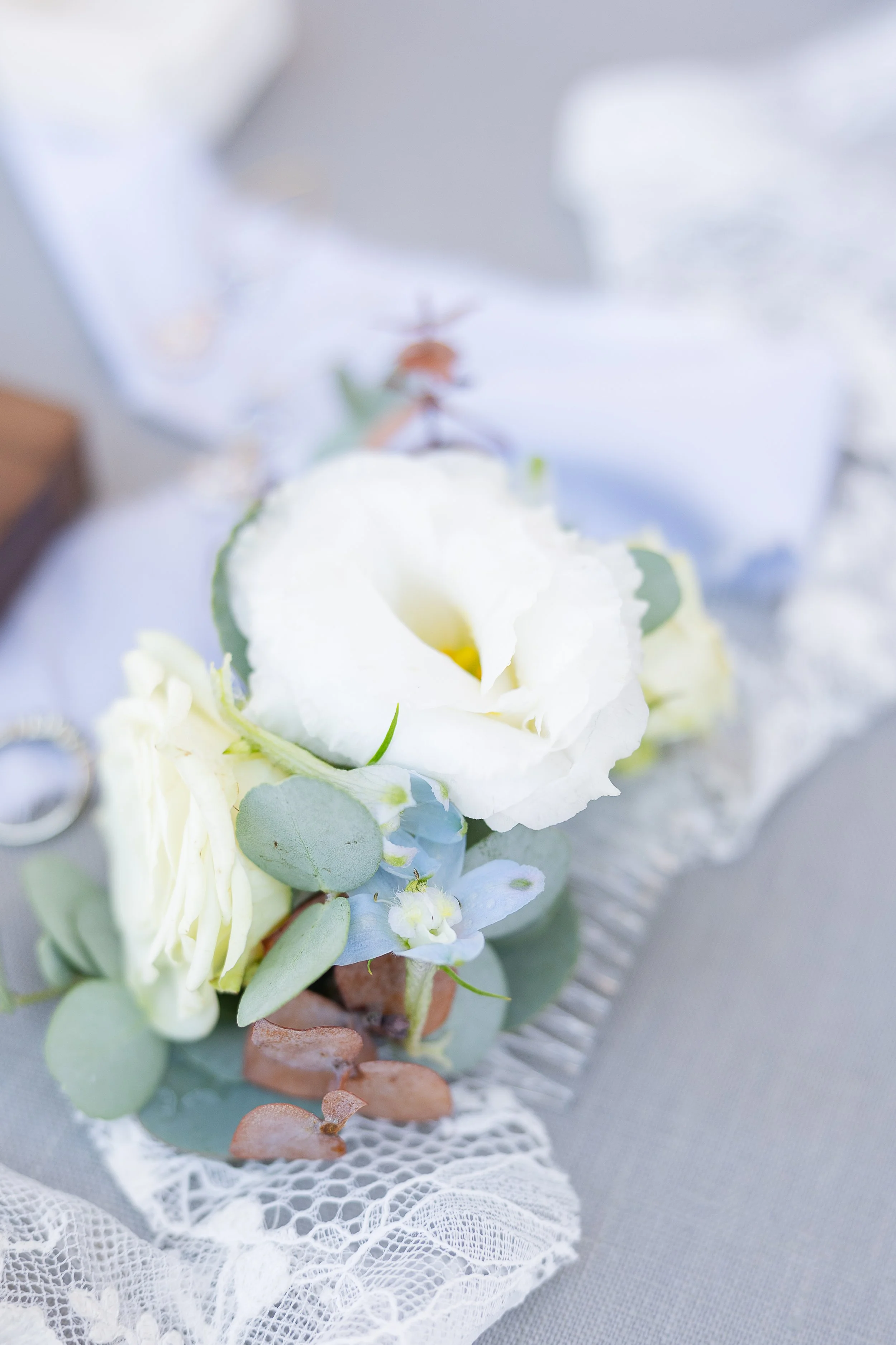 close up of a hair piece made of lisianthus, roses, and delphinium on lace ribbon, sonora ca